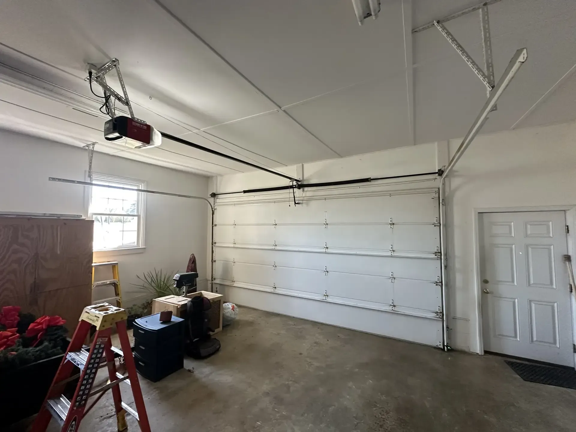 A garage with a garage door open and a ladder in it.