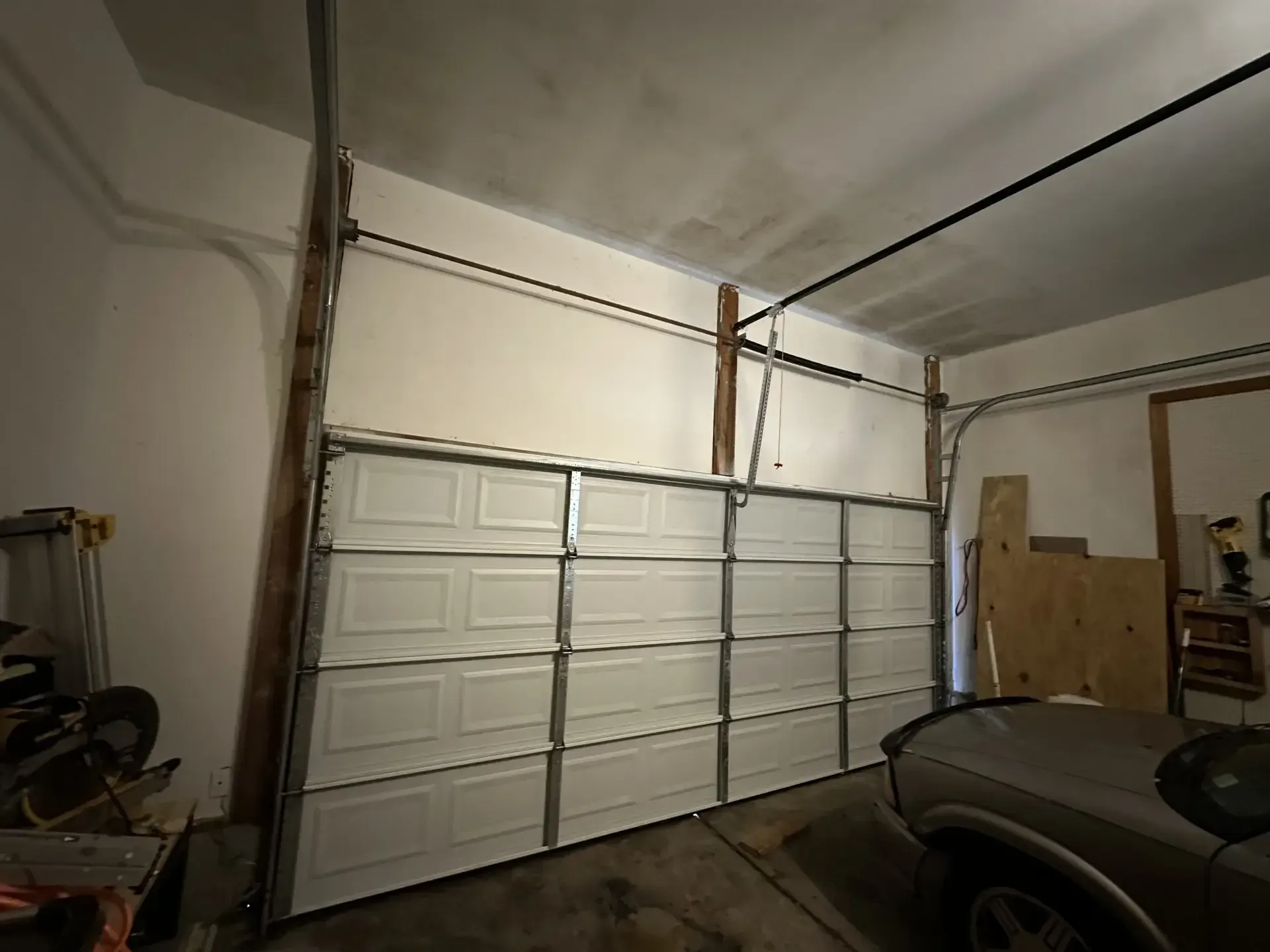 A car is parked in a garage with a garage door open.