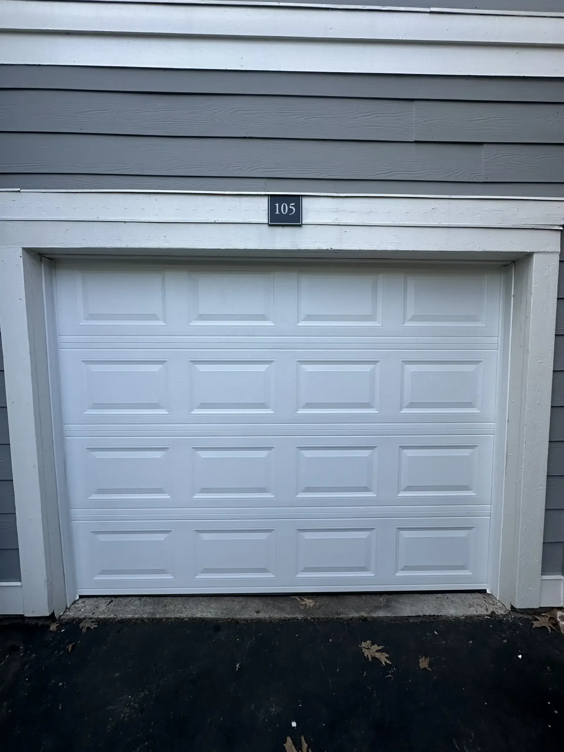 A white garage door is open on the side of a house.
