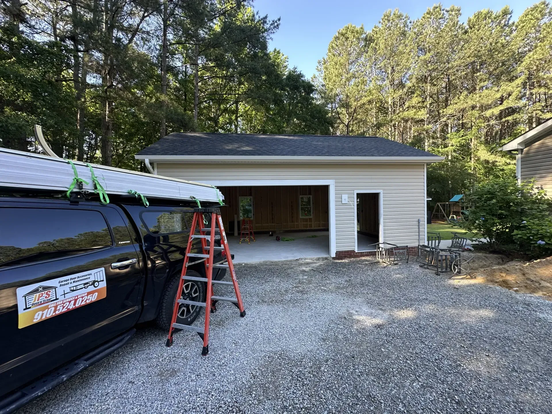 A black van is parked in front of a garage under construction.