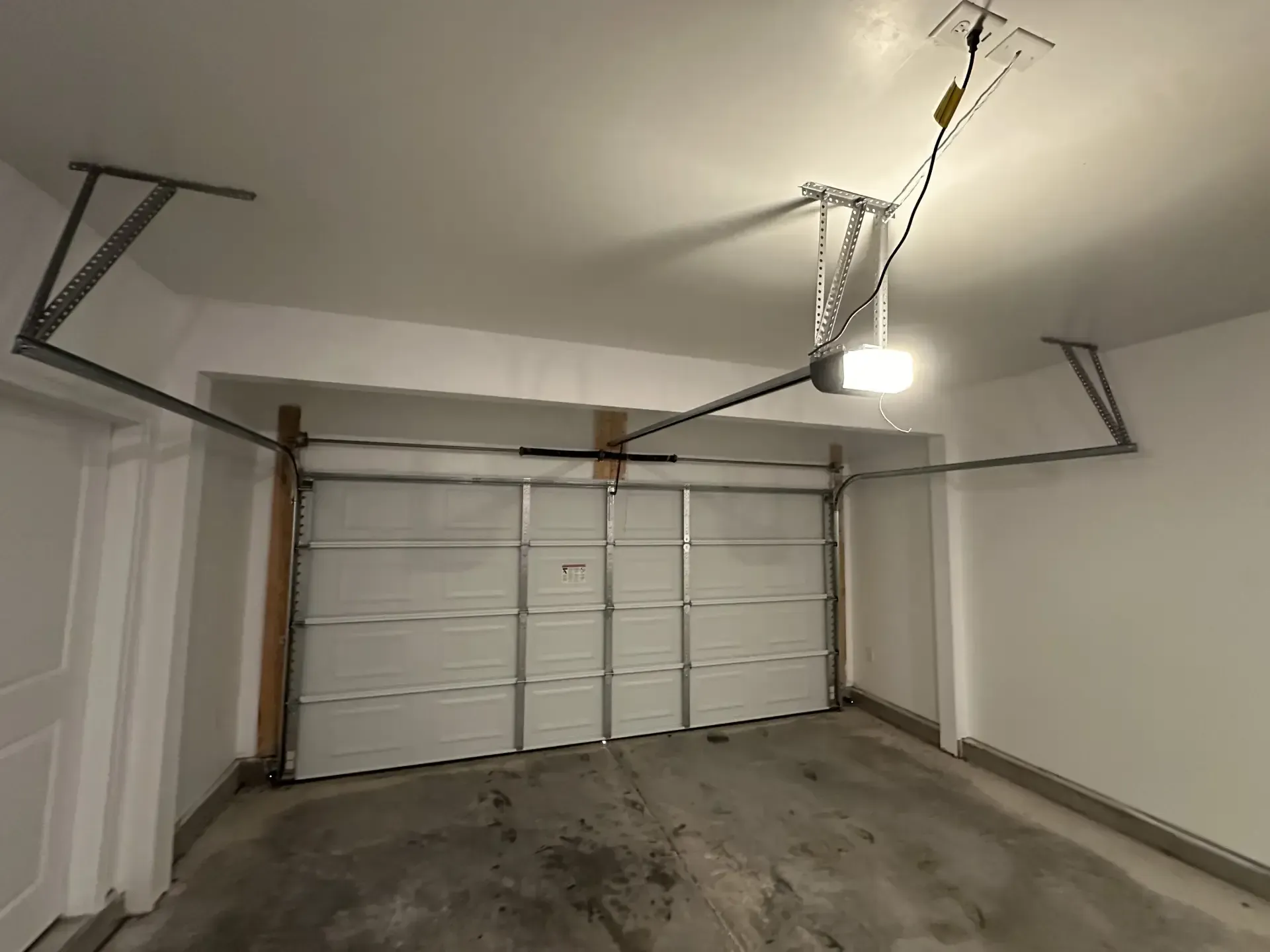 An empty garage with a garage door open and a garage door opener.