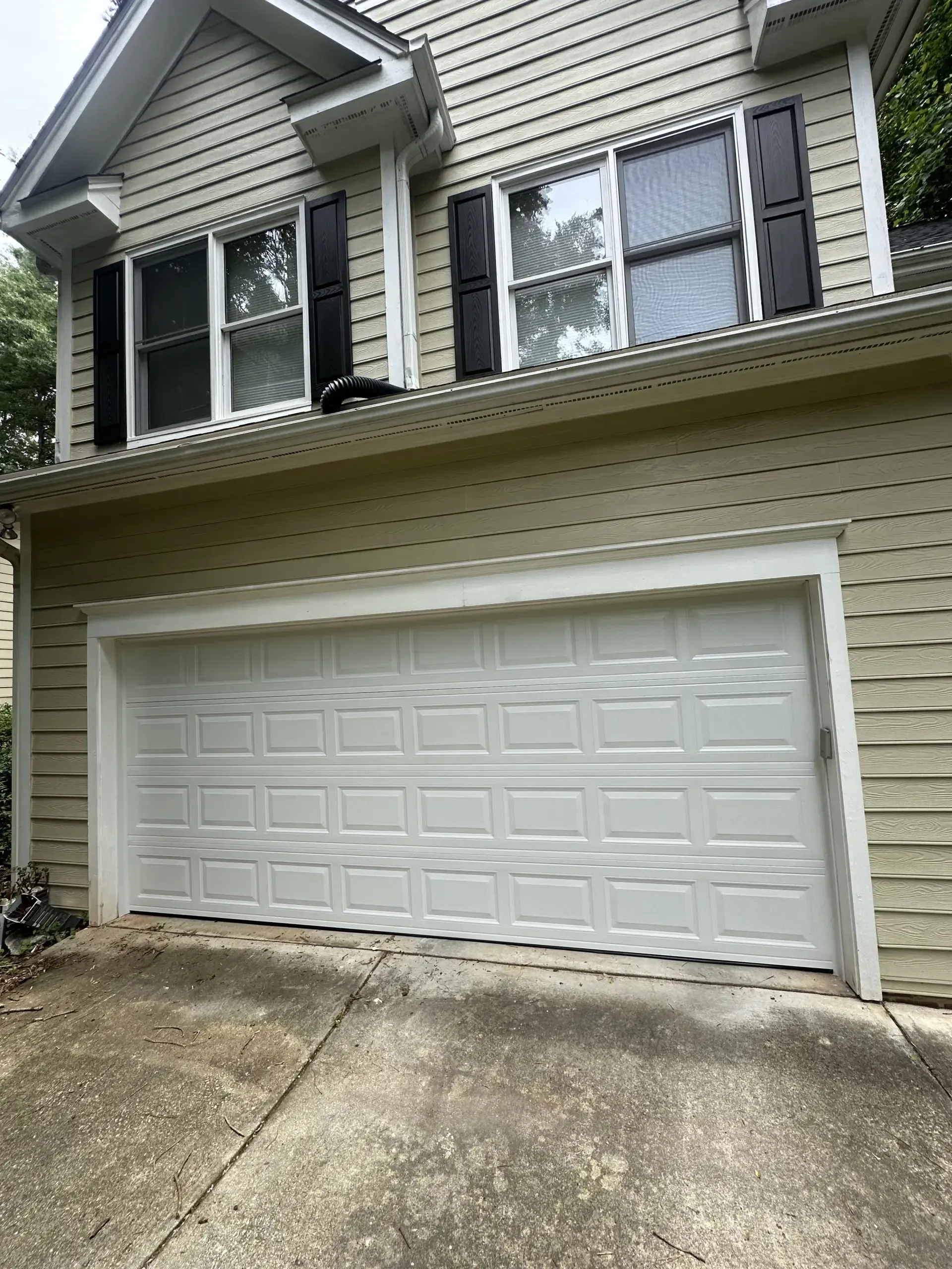 A large house with a white garage door and black shutters.