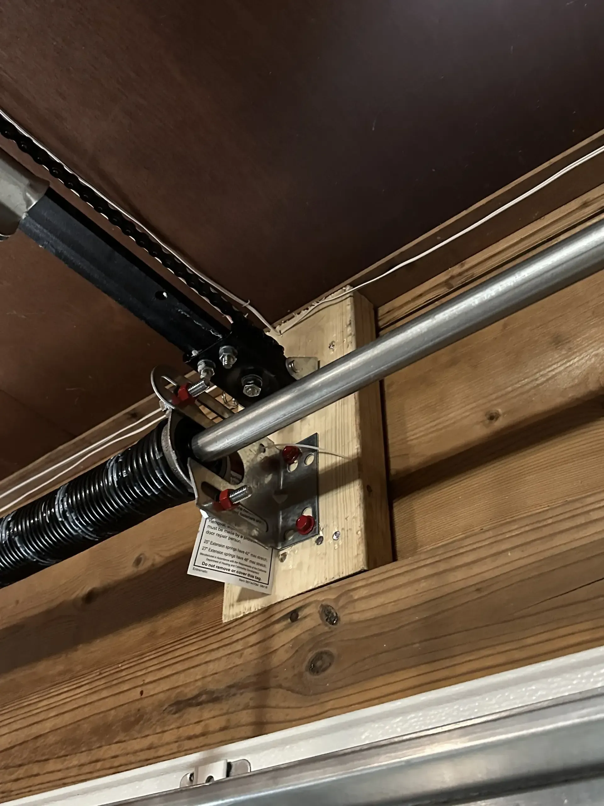 A close up of a garage door spring on a wooden wall.