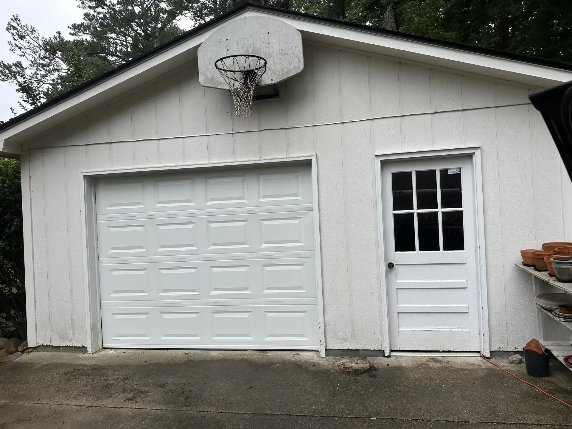 A white garage with a basketball hoop on top of it.