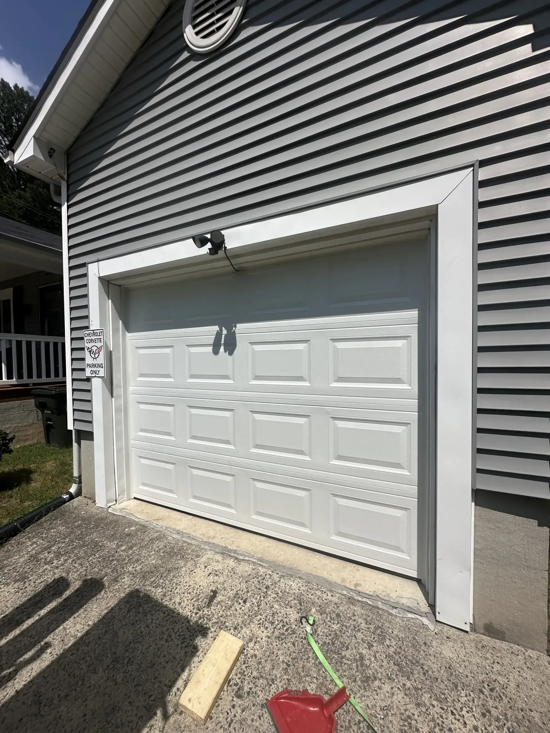 A white garage door is sitting on the side of a house.