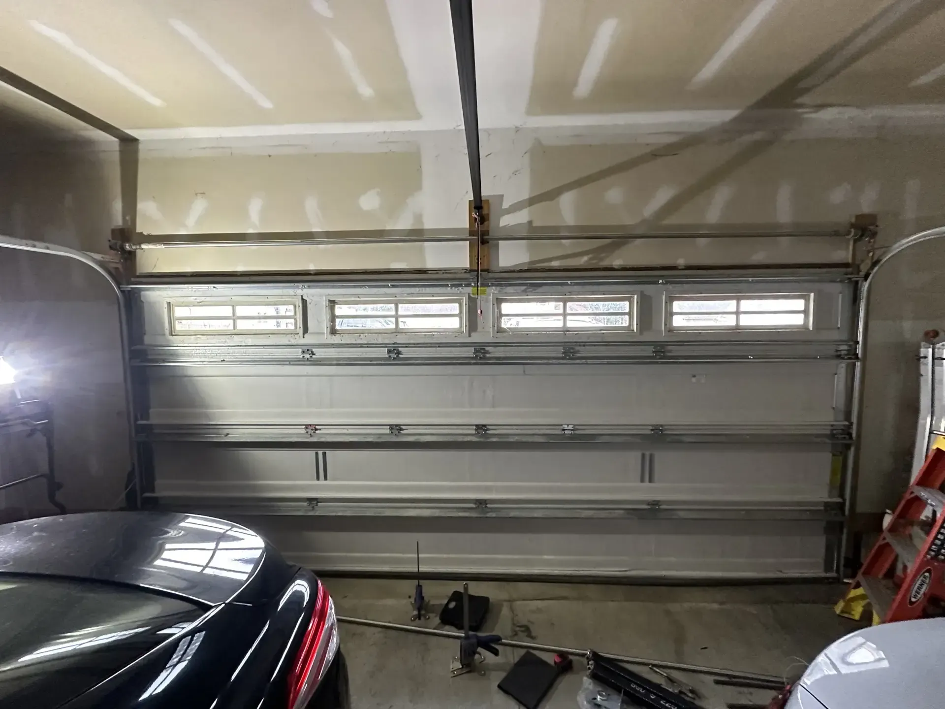 A car is parked in a garage with a garage door open.