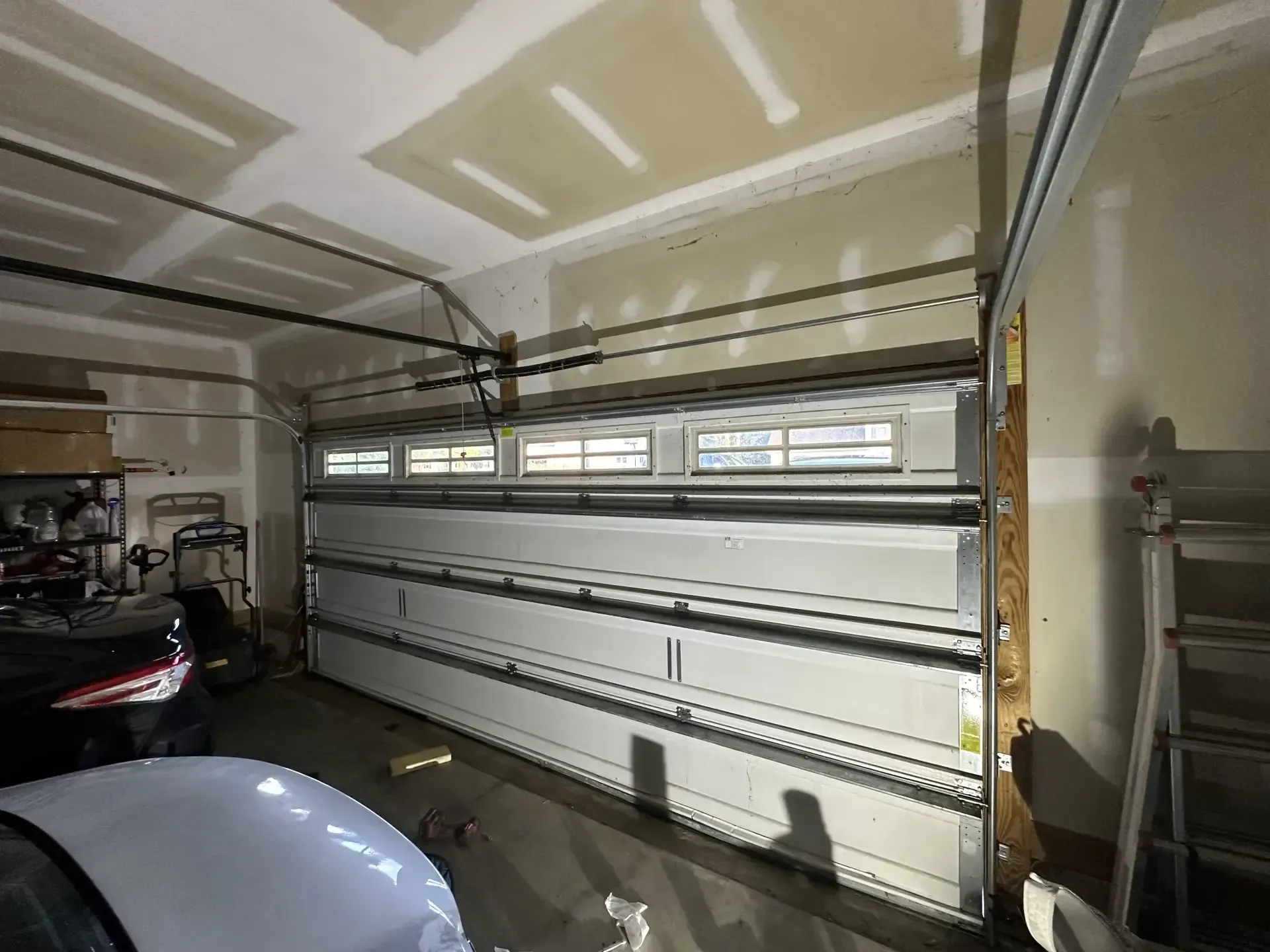 A white car is parked in a garage with a garage door open.