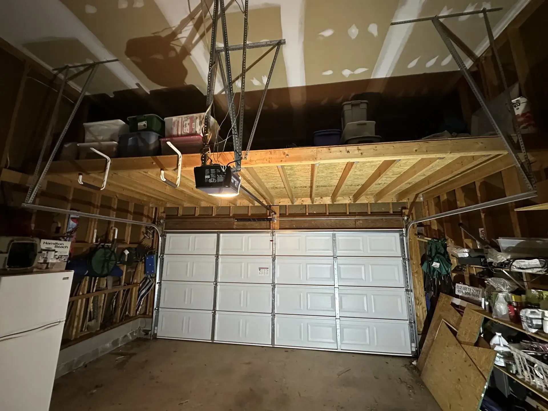 A garage with a garage door open and a loft above it.