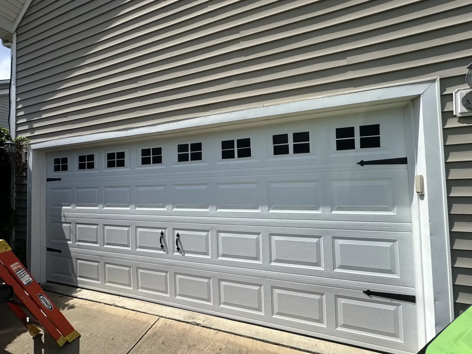 A white garage door is sitting on the side of a house.