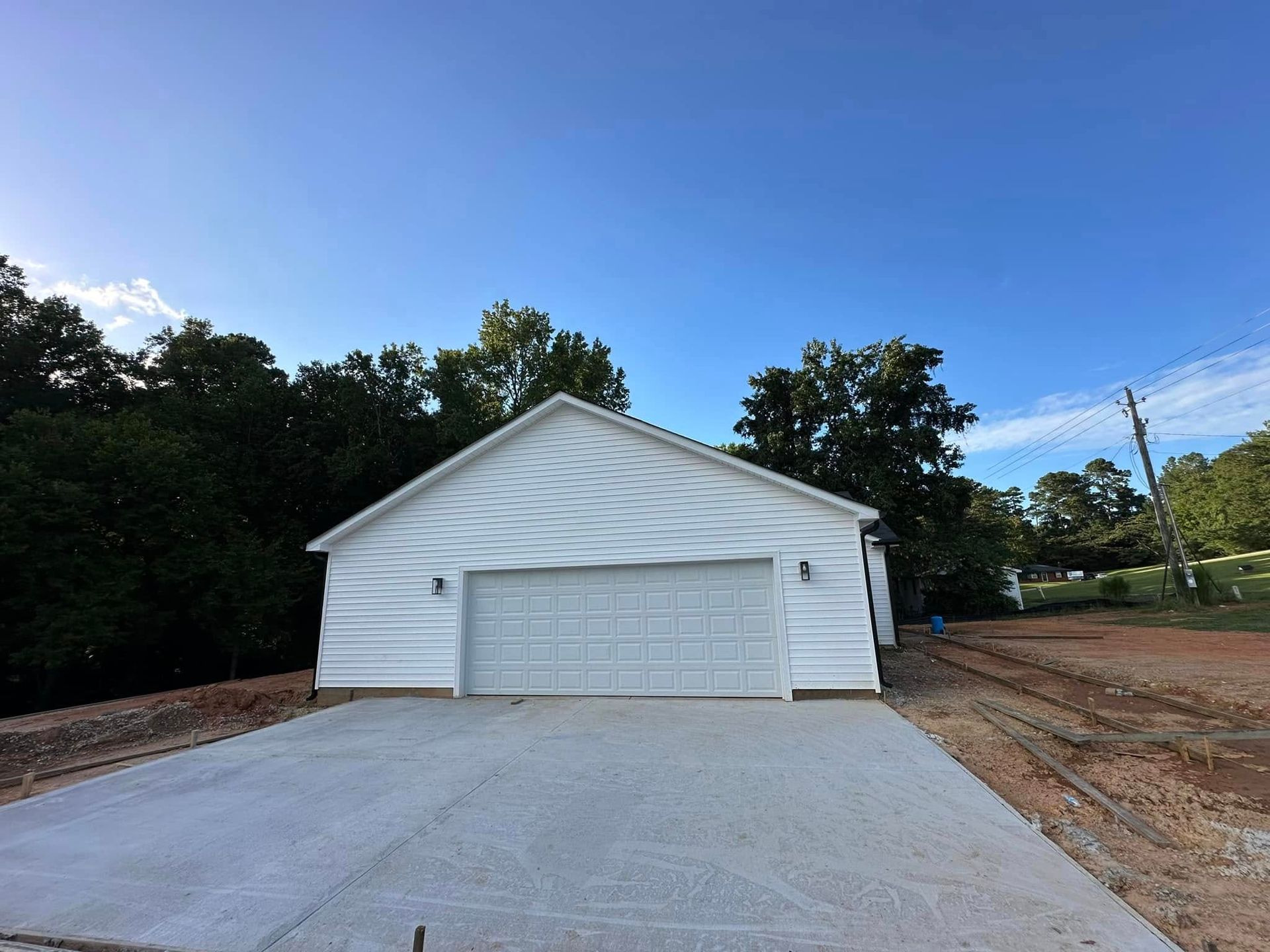 A white garage with a concrete driveway in front of it