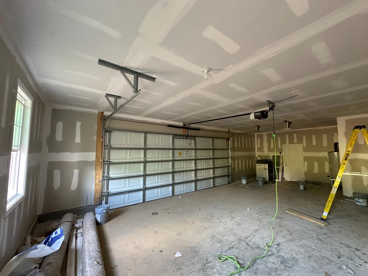 An empty garage with a garage door open and a ladder.