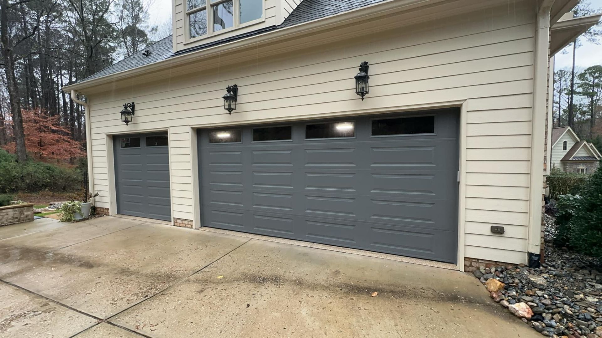 There are three garage doors on the side of a house.