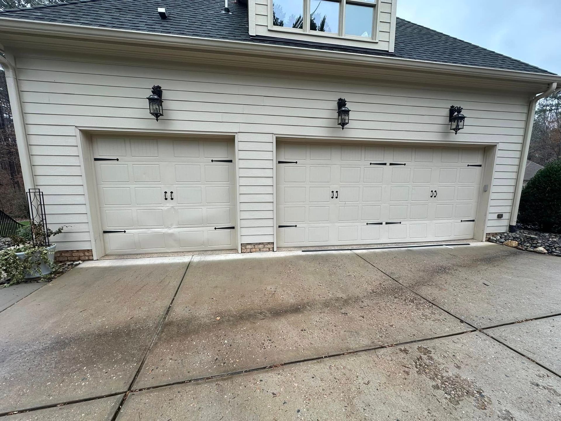 A white house with two garage doors and a concrete driveway.