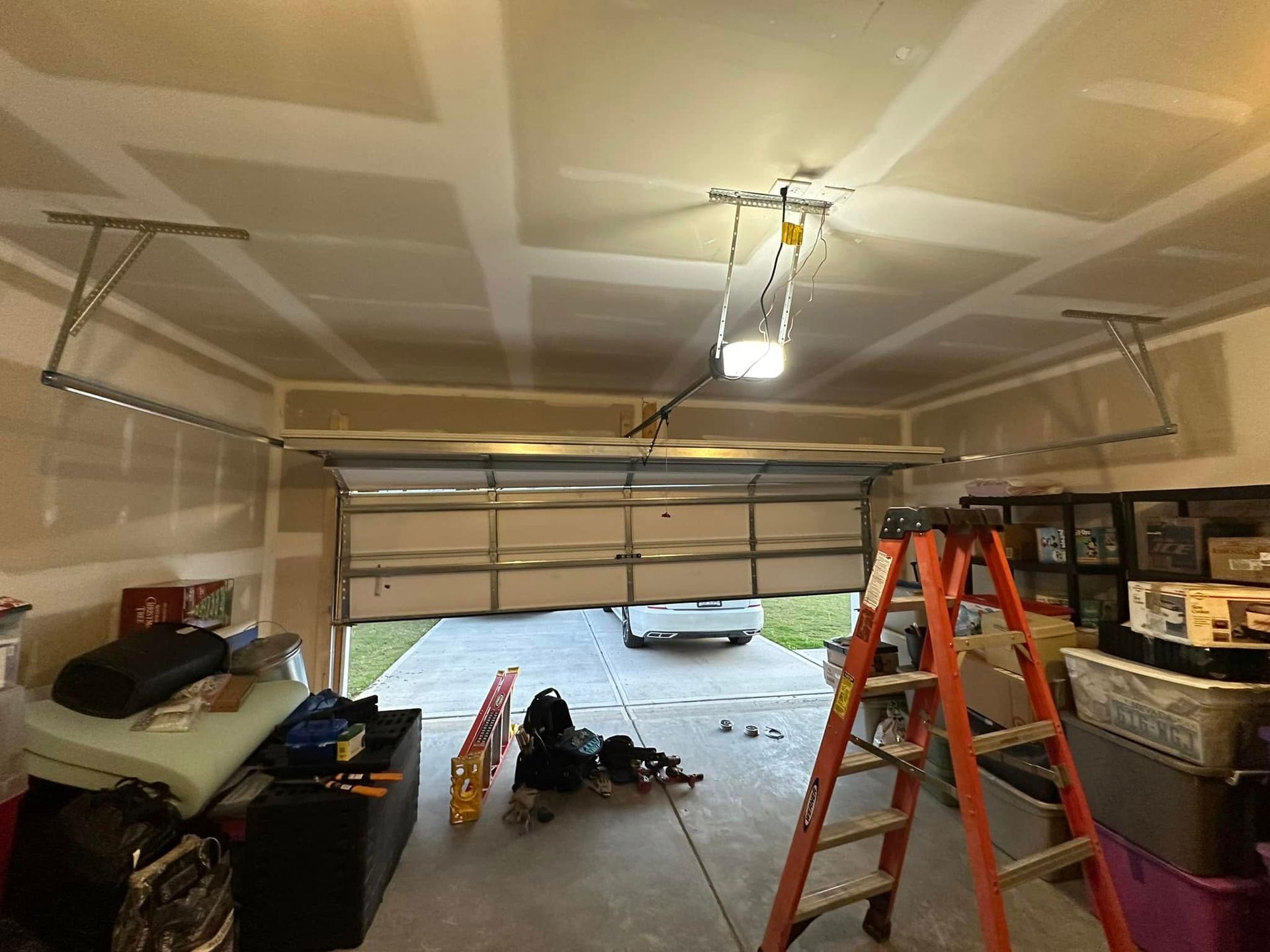 A garage with a garage door open and a ladder in it.