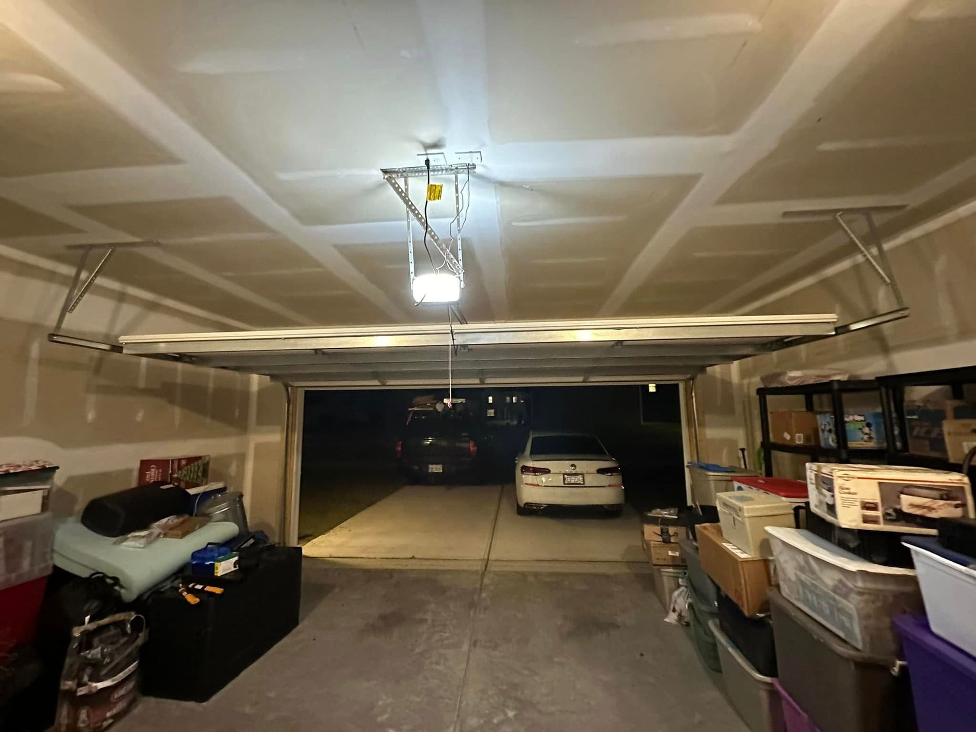 A garage filled with lots of boxes and a car parked in it.