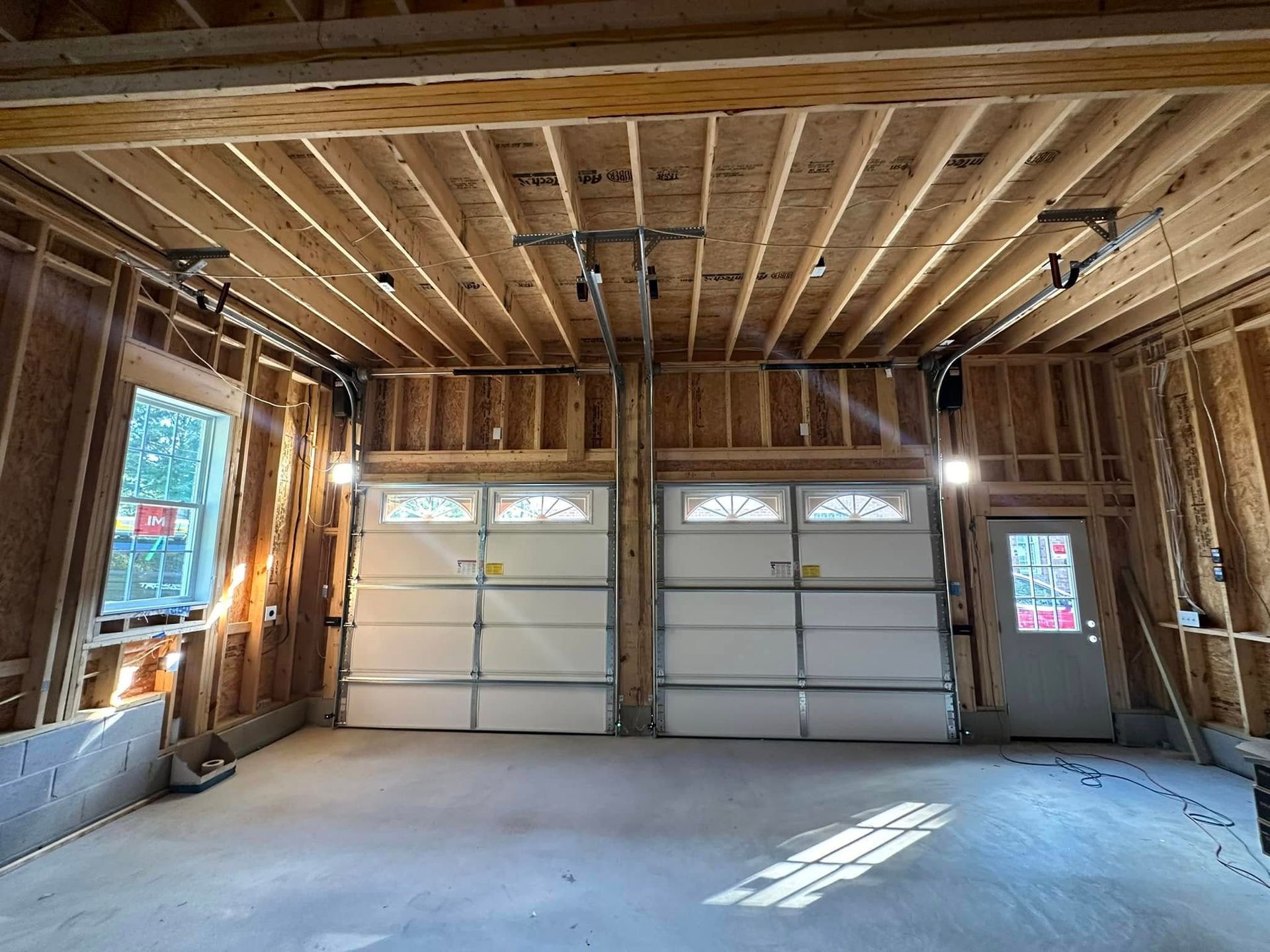 A garage under construction with two garage doors and a ceiling.