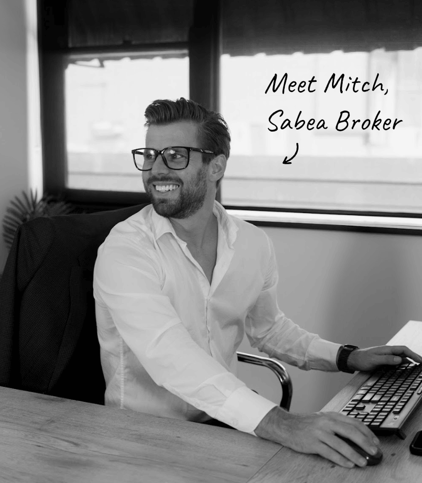 Four people in a meeting around a table in a modern office with glass walls and a TV.