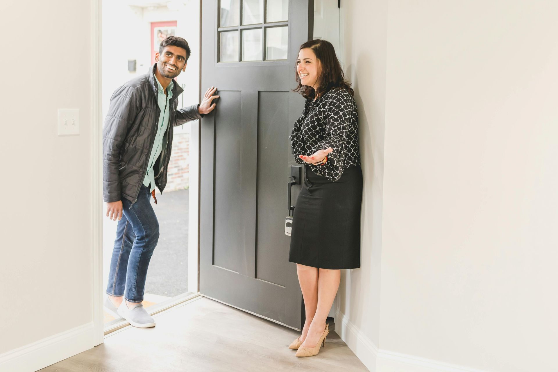 Man opening a door, with real estate woman waiting inside, representing a new chapter after separati