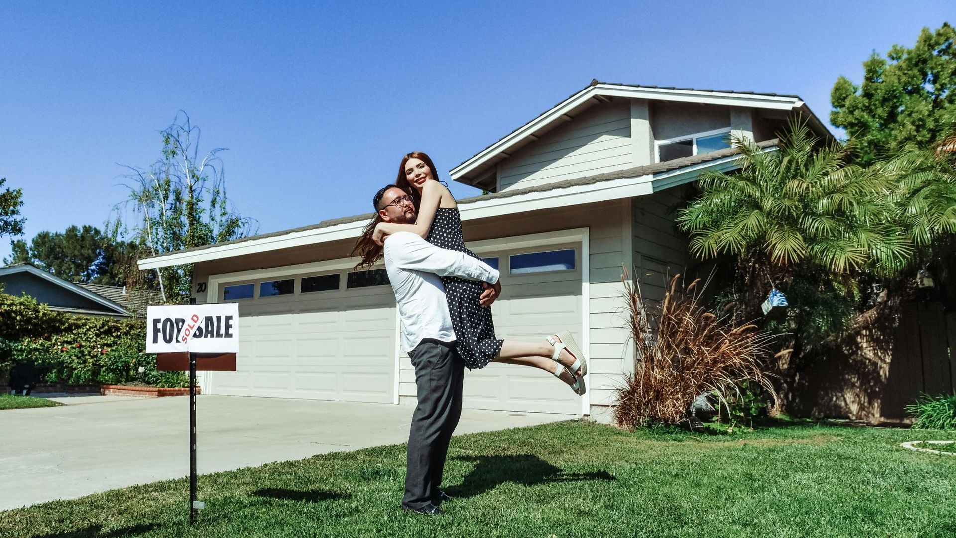 Man holding woman in front of a house with a 