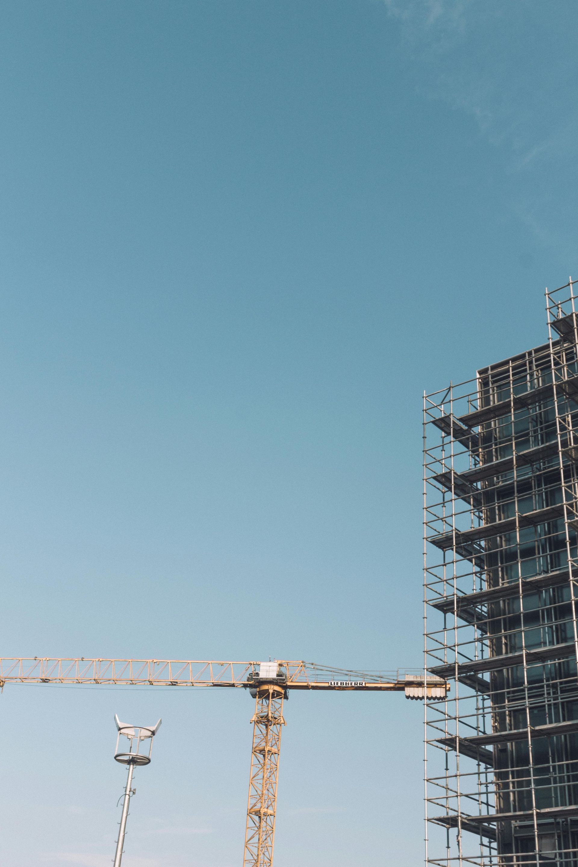 Construction site with a crane and scaffolding against a blue sky.