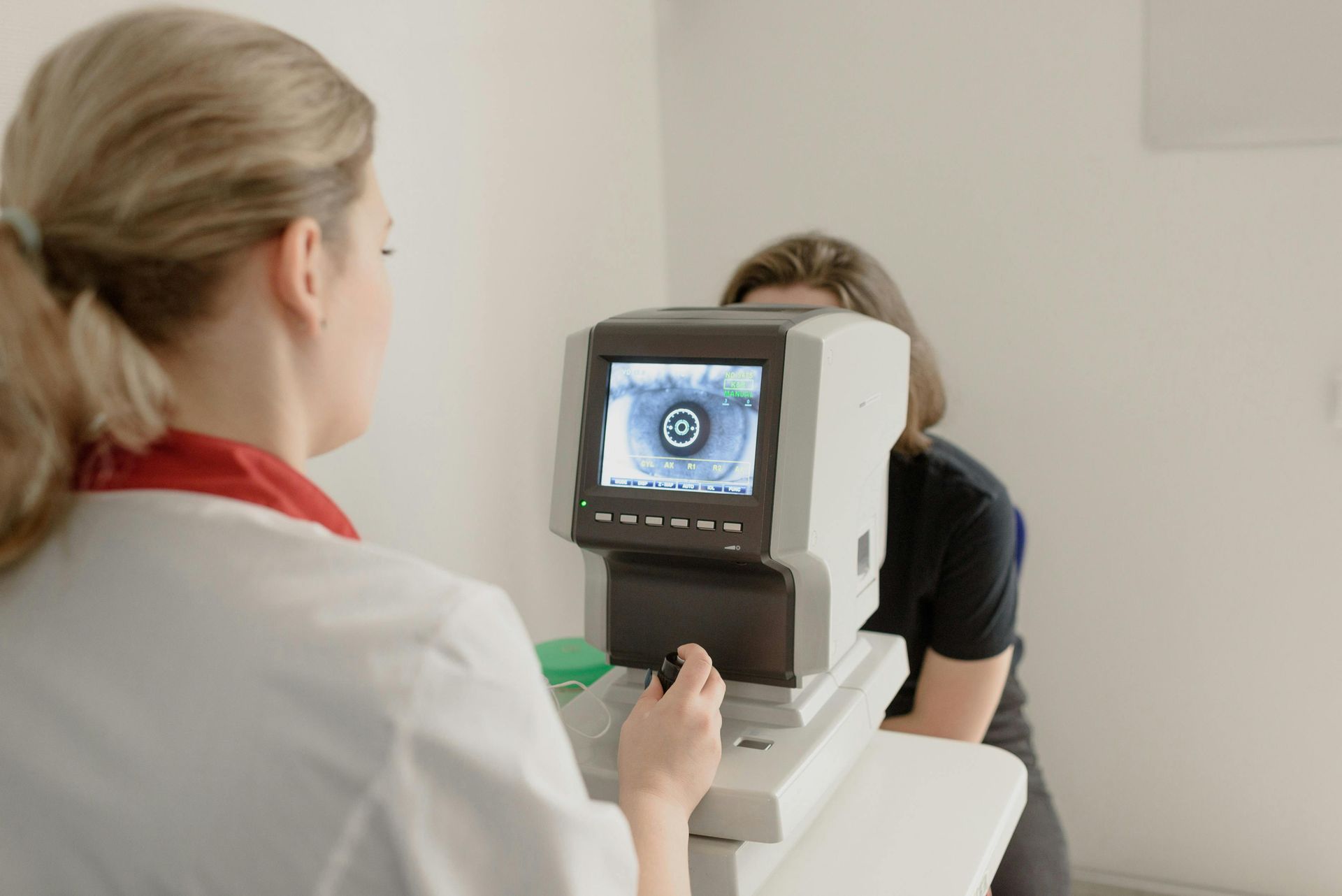 Optometrist using an eye exam machine on a patient in a medical office.
