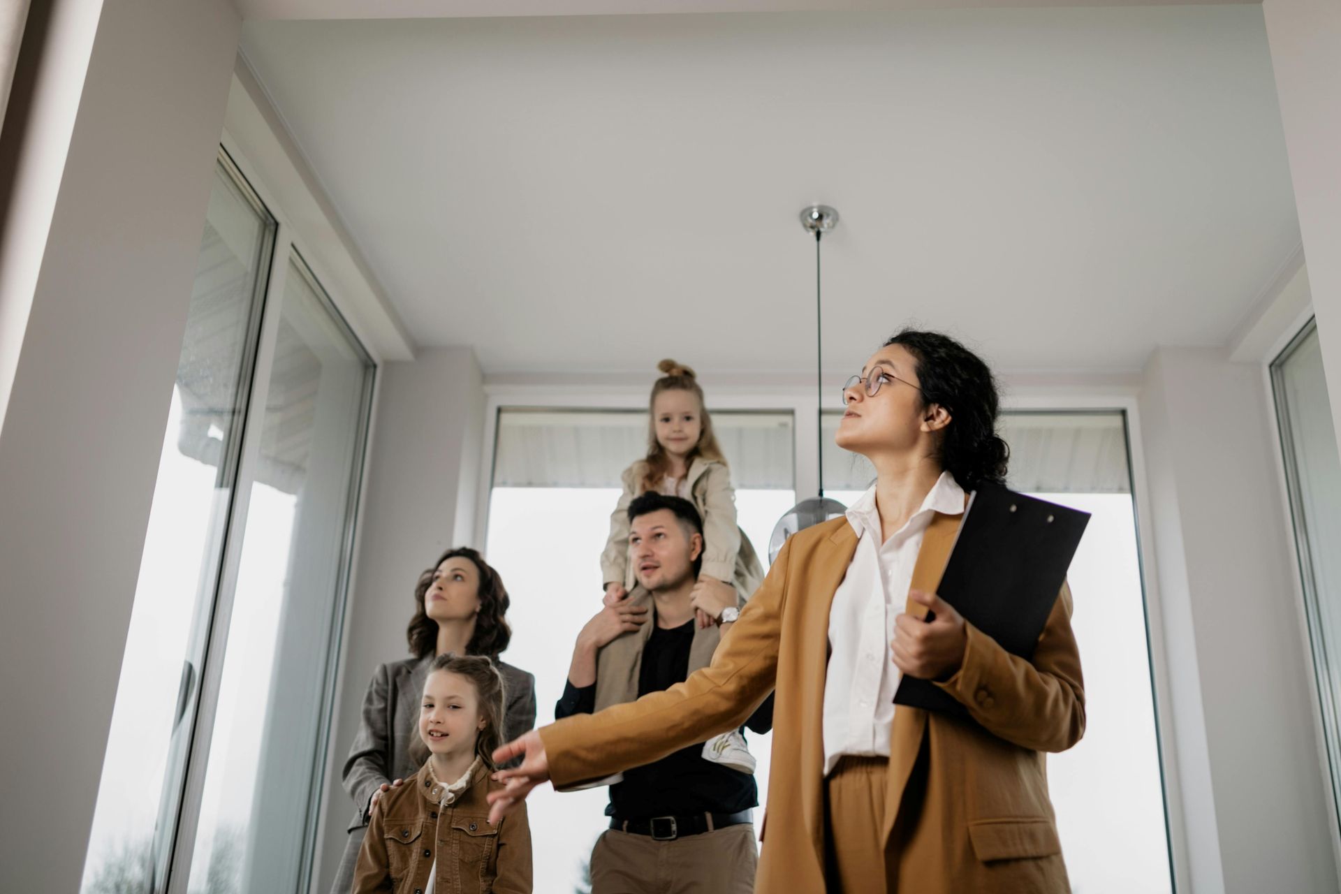 Real estate agent showing a family a light-filled apartment. The family looks up, observing the space.