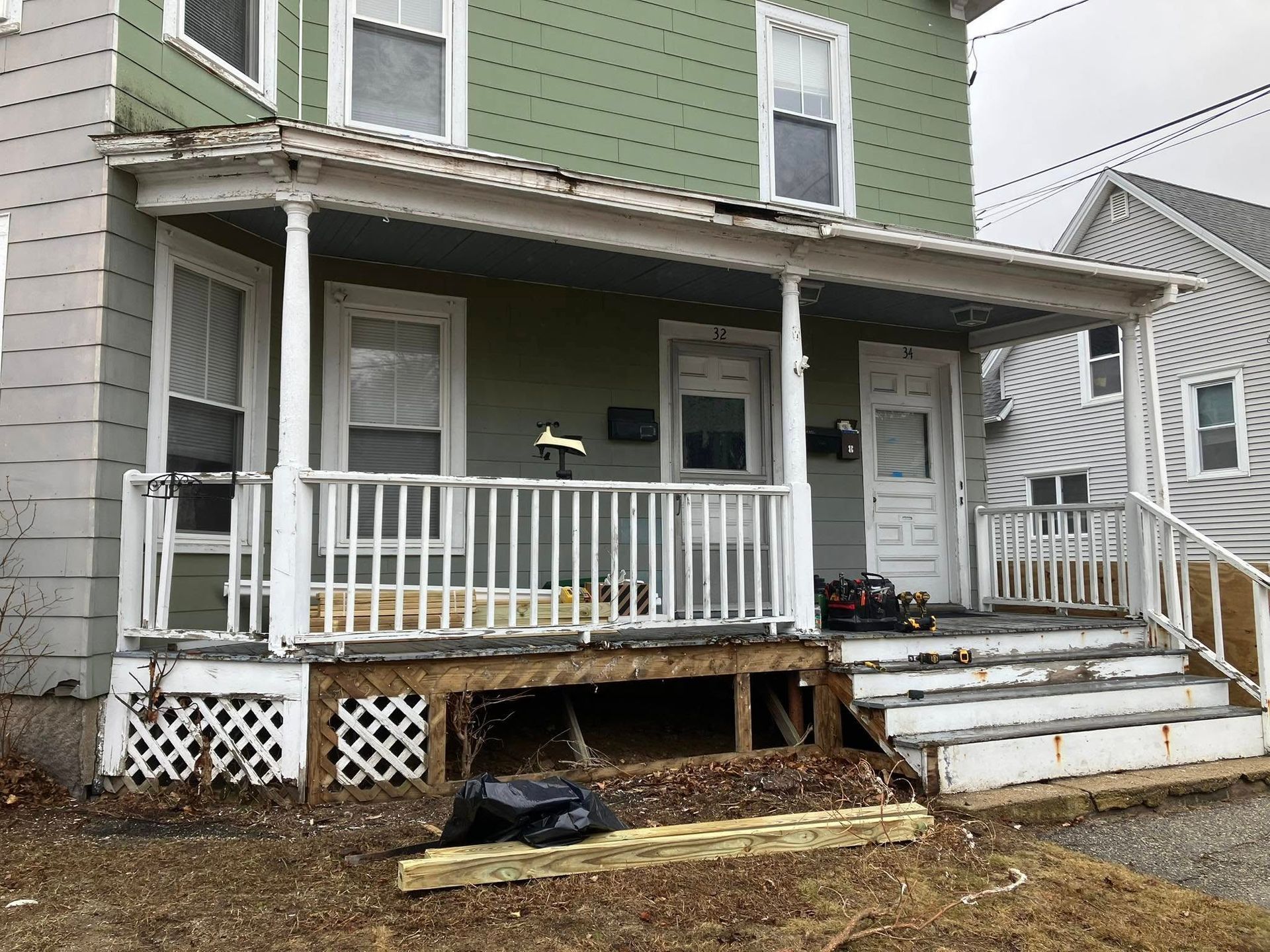 A green house with a white porch and stairs.