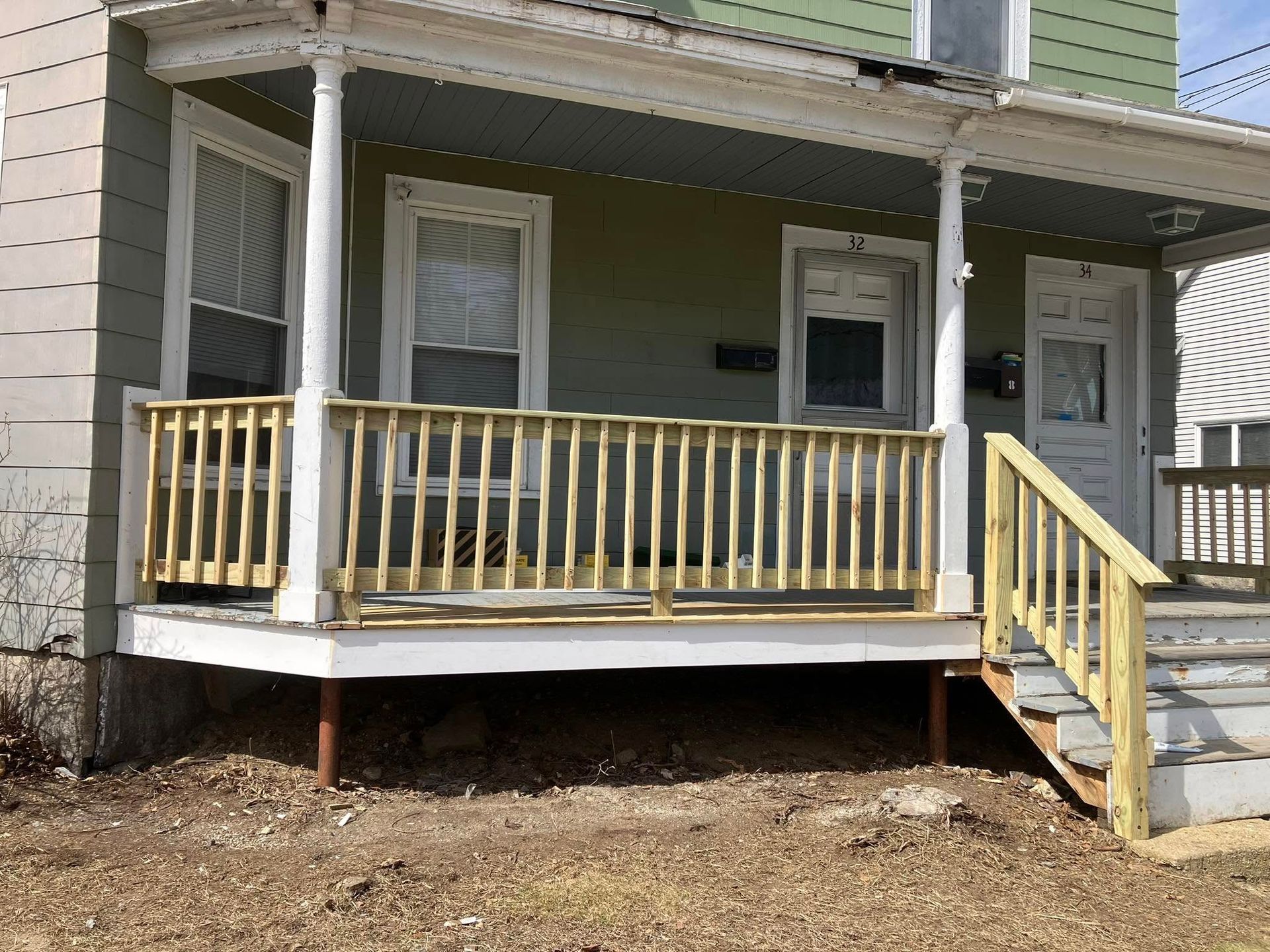 The front porch of a house has a wooden railing and stairs