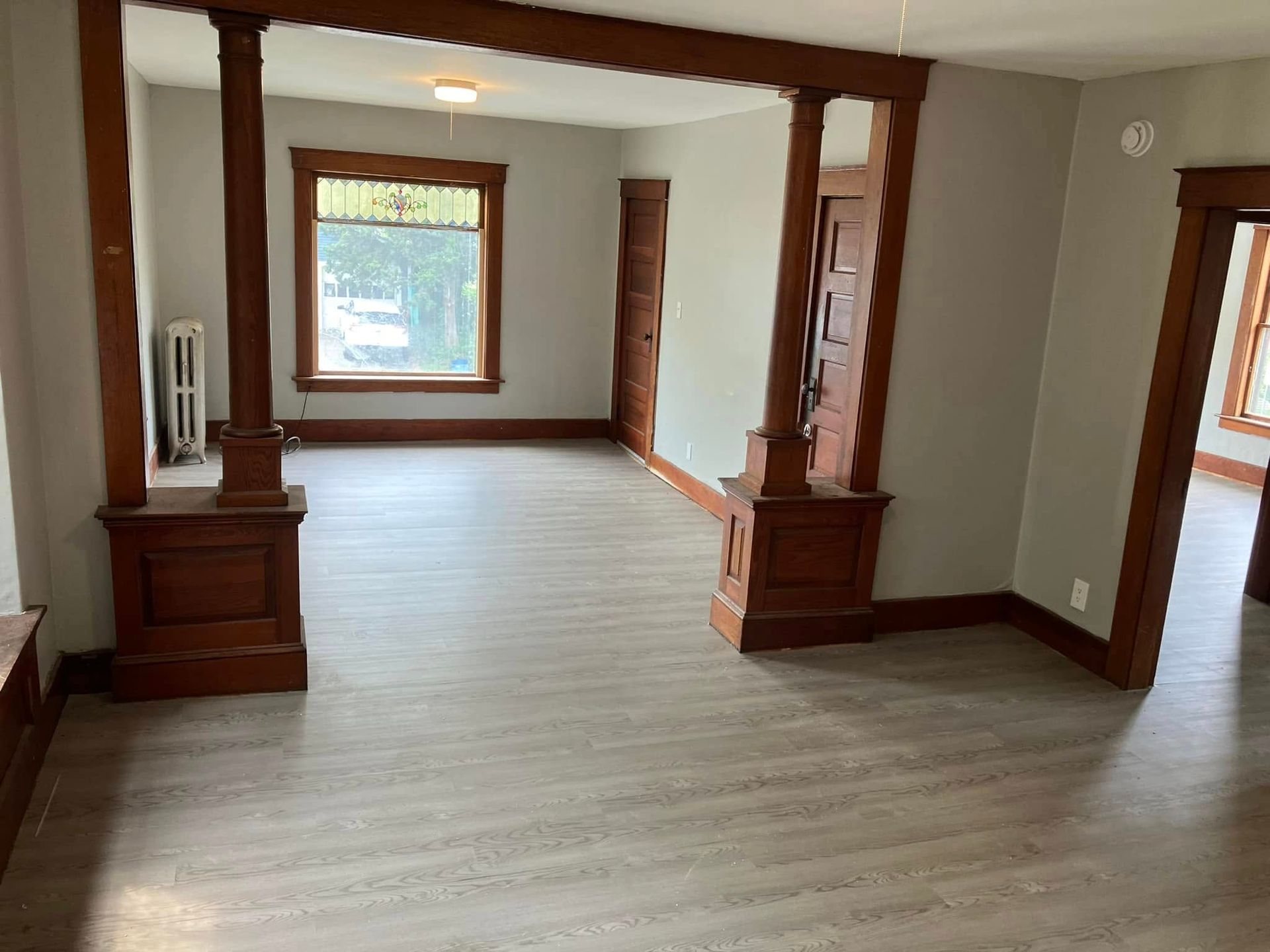 An empty living room with hardwood floors and a window.