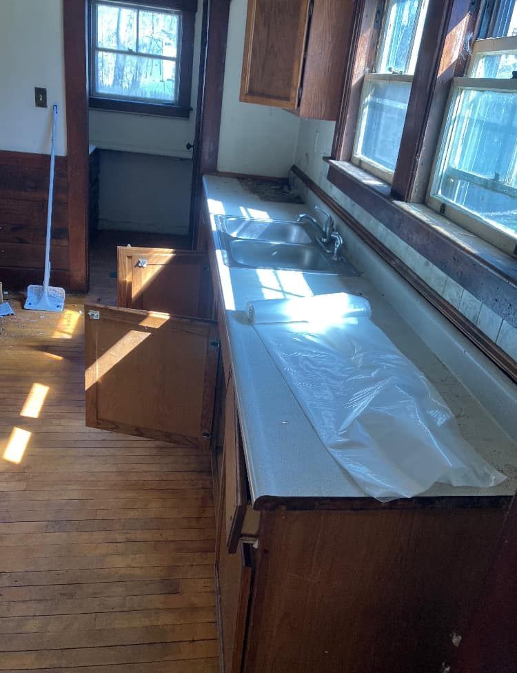 A kitchen with wooden cabinets , a sink , and a window.