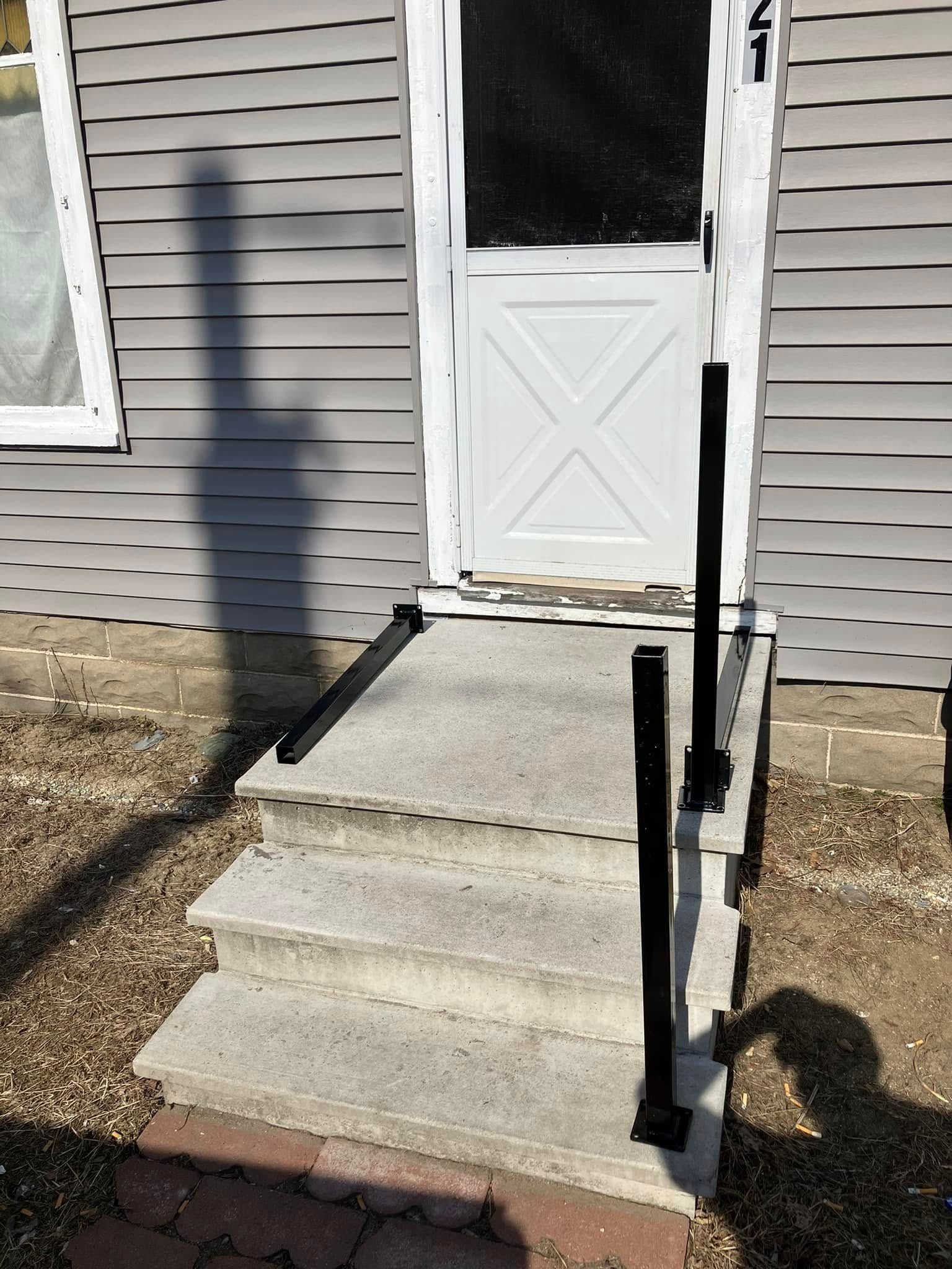 A white door with a black railing and stairs leading up to it.