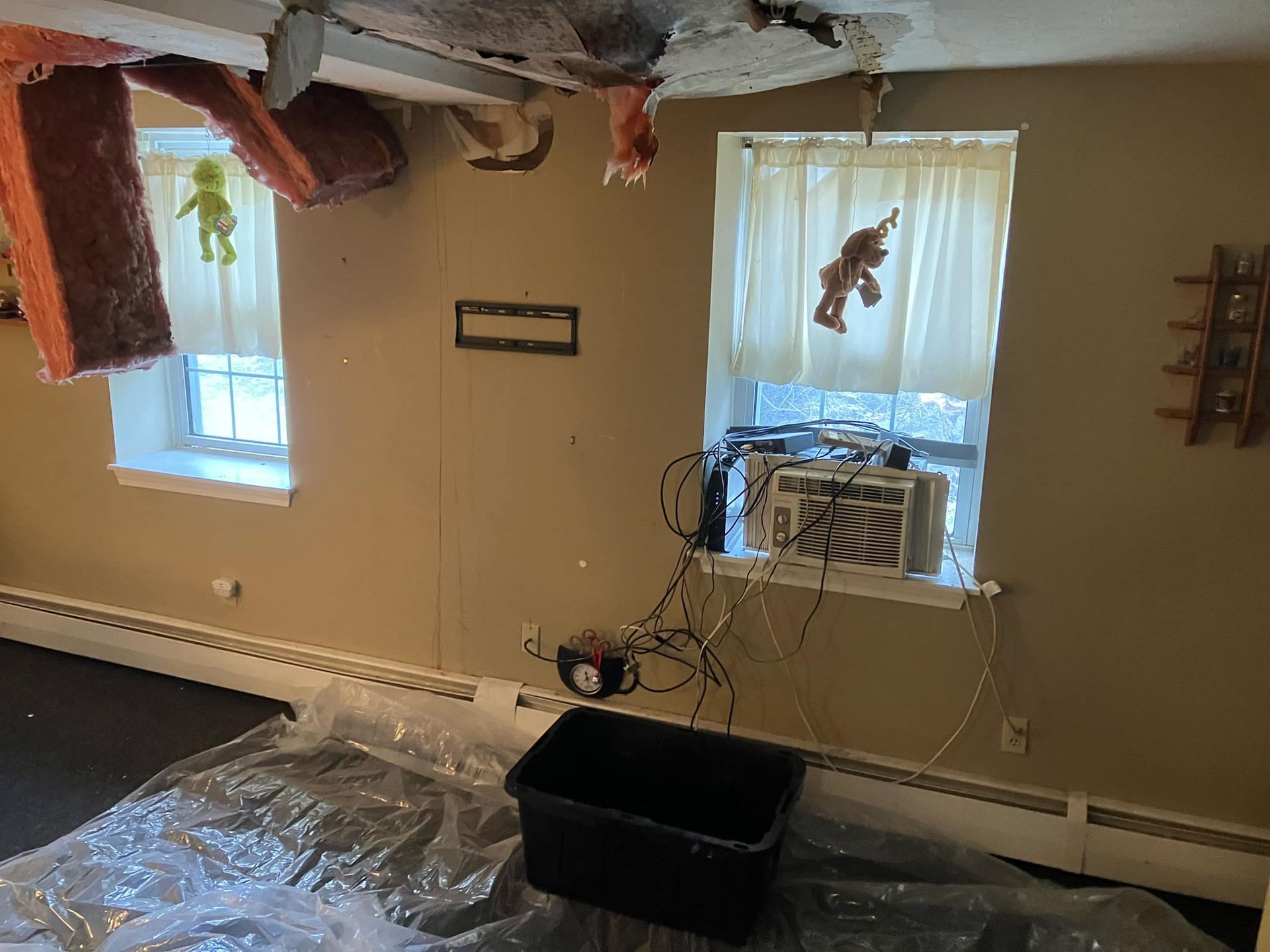 A room with a box on the floor and a window with a monkey hanging from the ceiling.