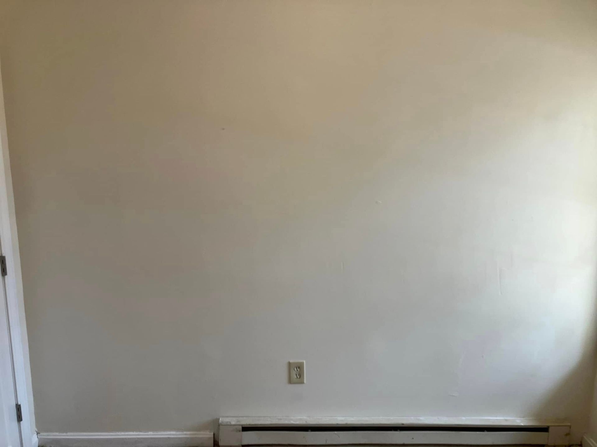 A room with a white wall and a radiator on the floor.