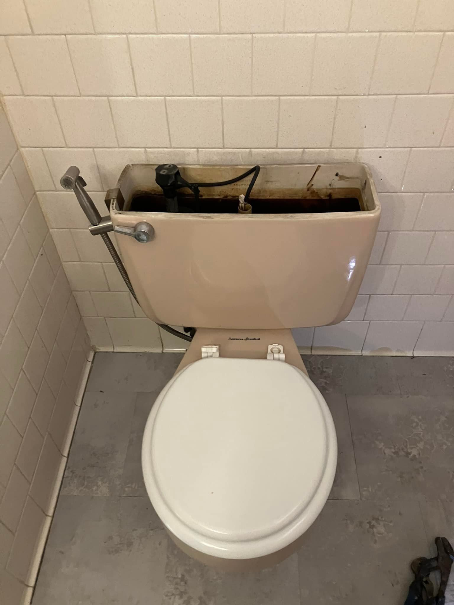 A toilet with a shower head attached to it in a bathroom.