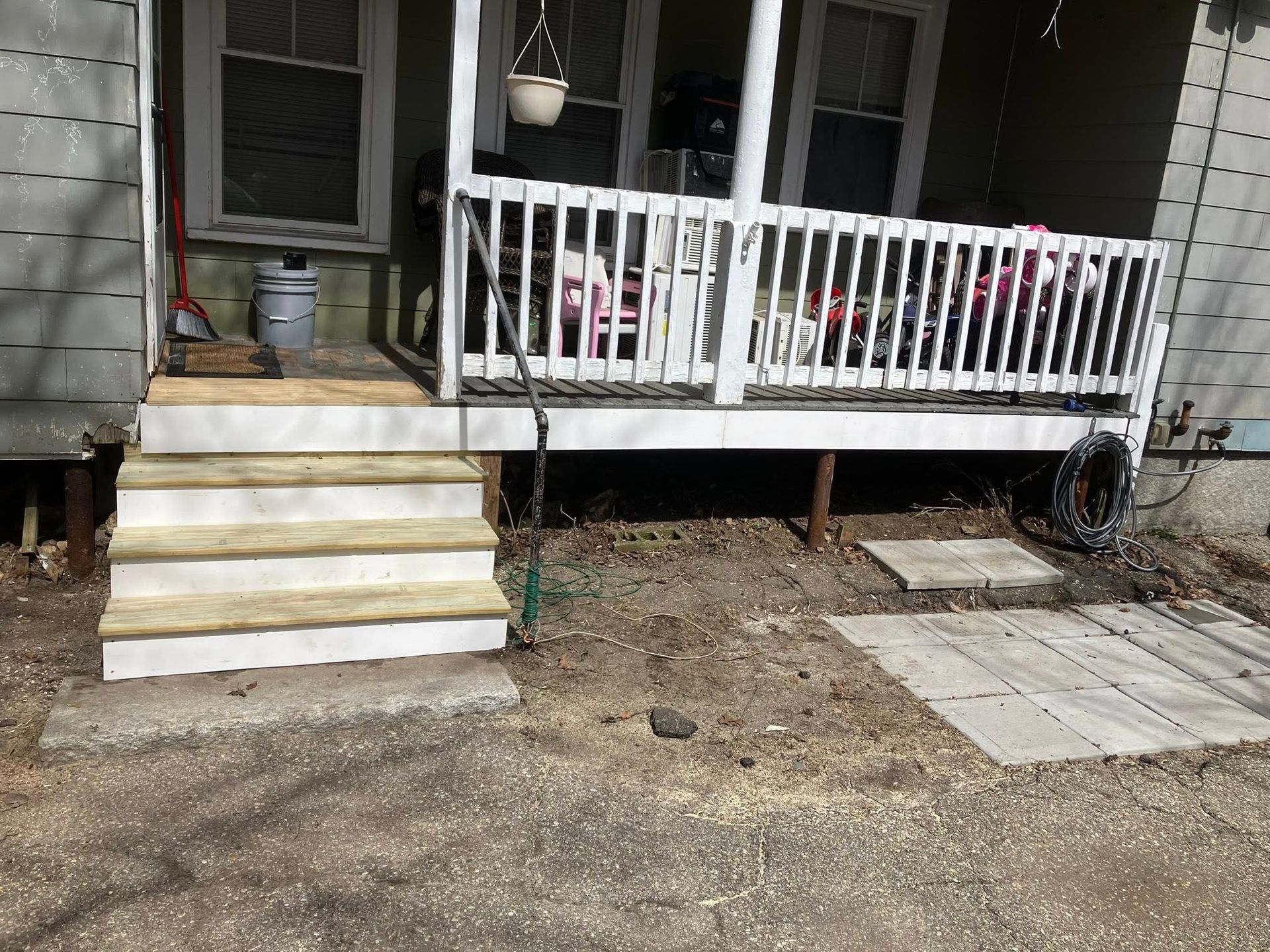 A porch with stairs leading up to it and a white railing.
