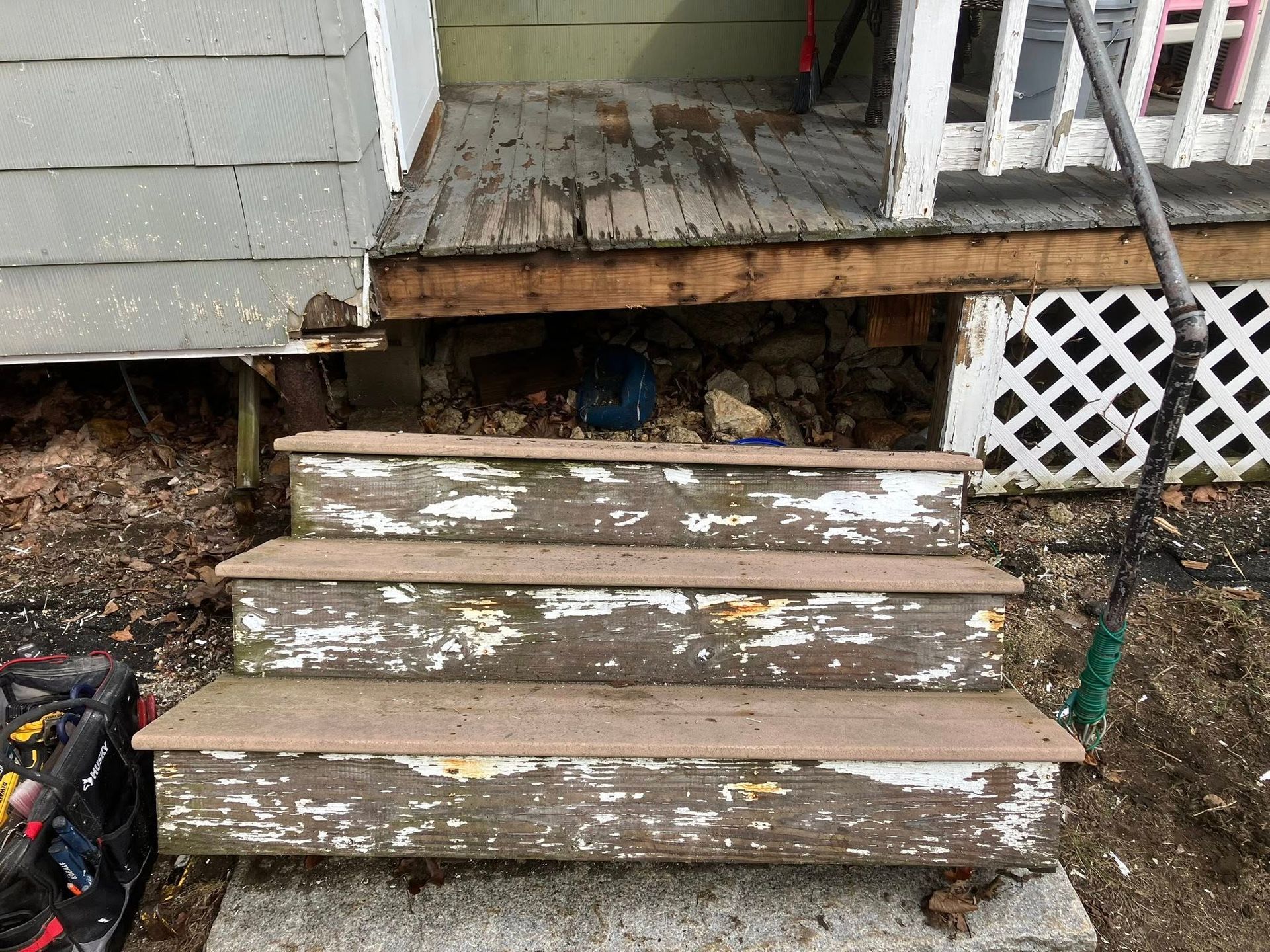 A set of wooden stairs leading up to a porch of a house.