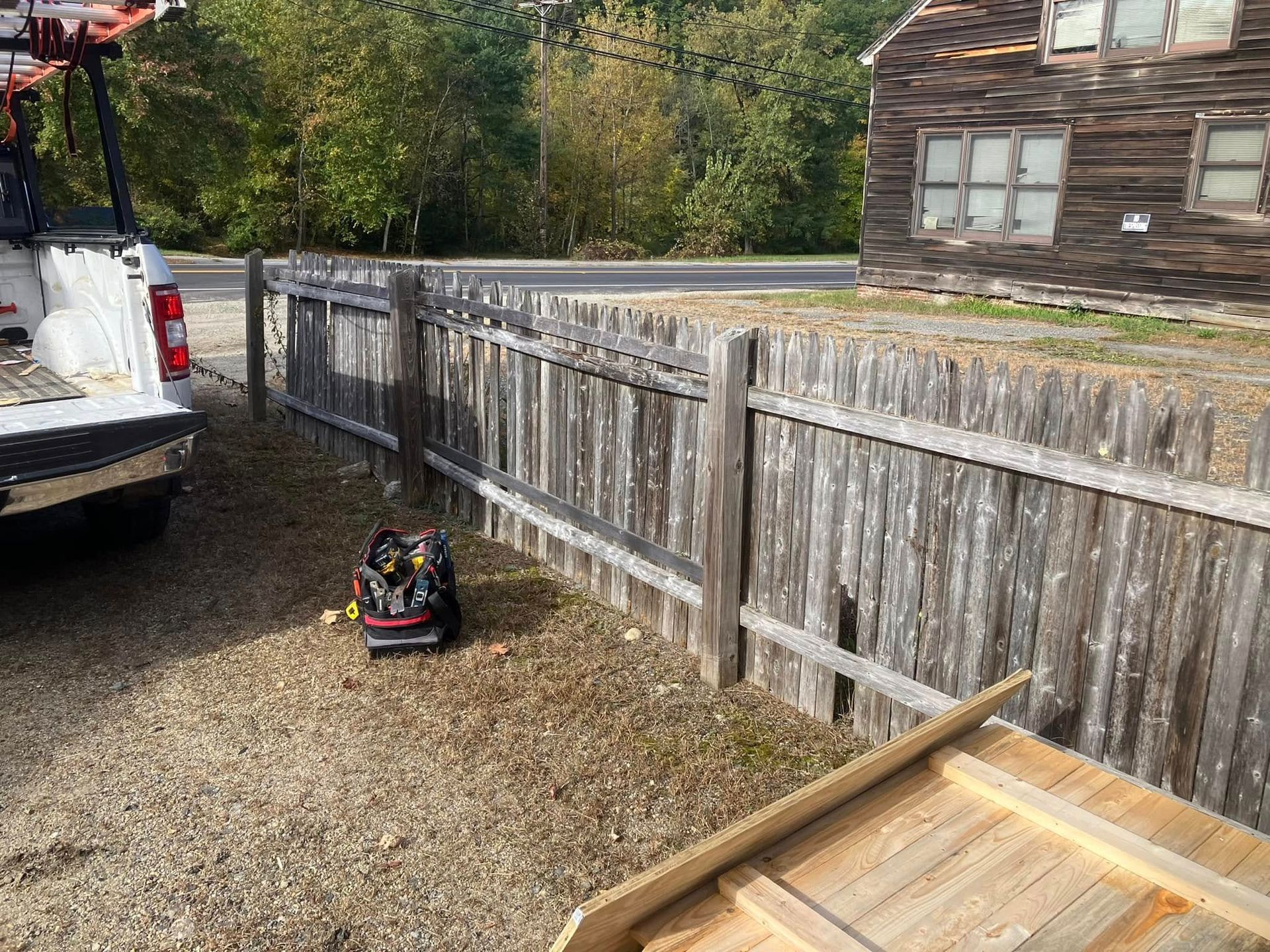 A white truck is parked next to a wooden fence.