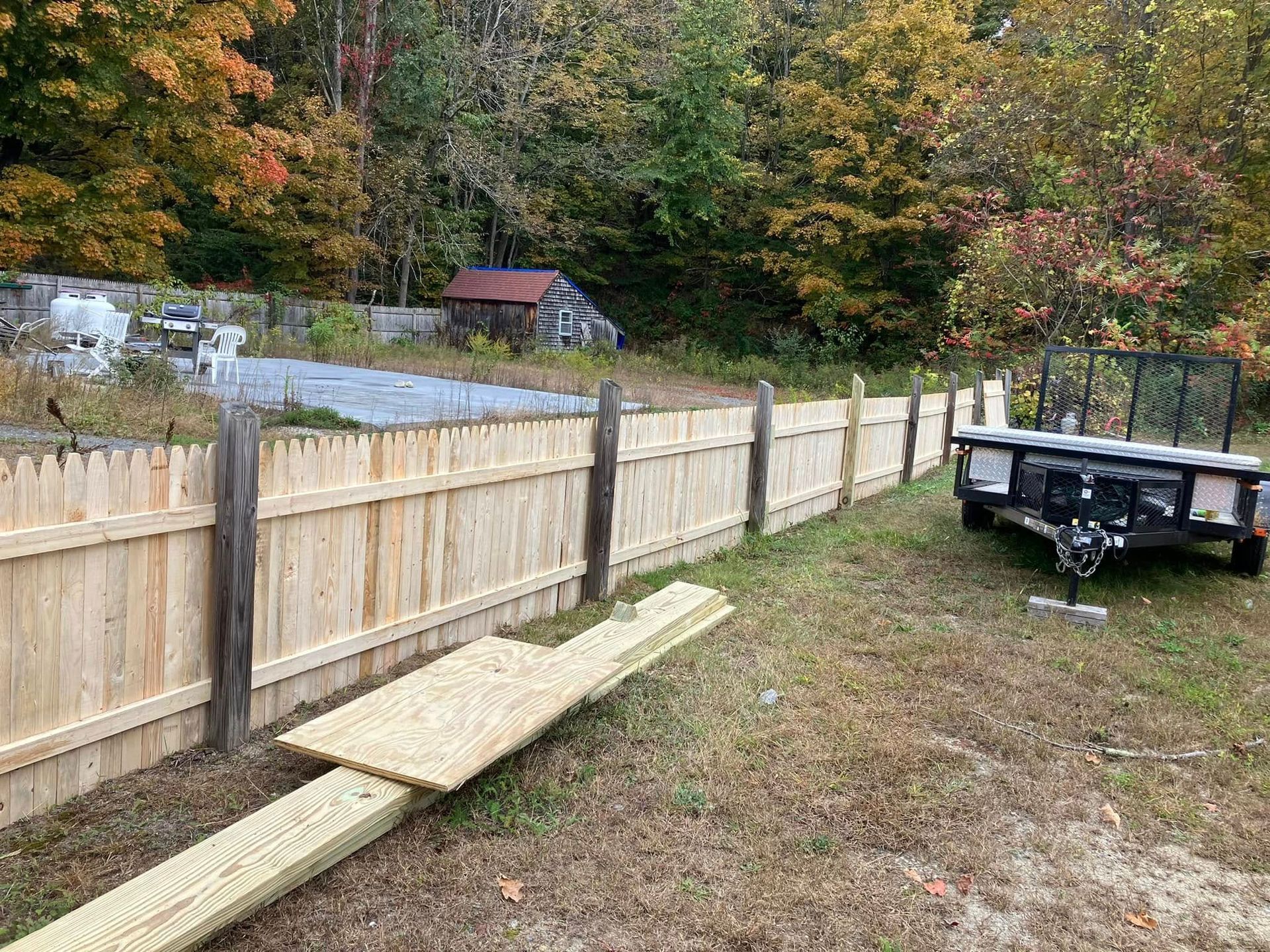 A wooden fence is being built in a yard next to a trailer.