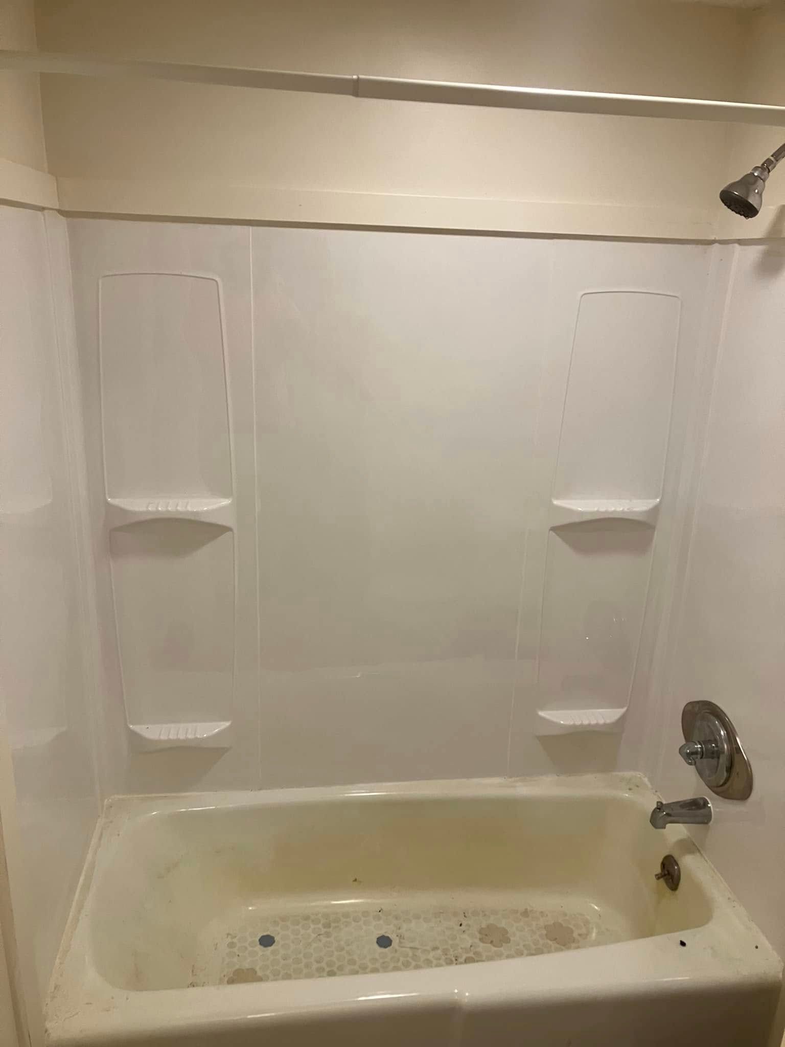A bathtub with a shower stall and shelves in a bathroom.