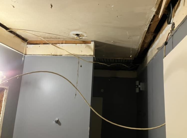 A room with a ceiling that is missing a piece of wood.