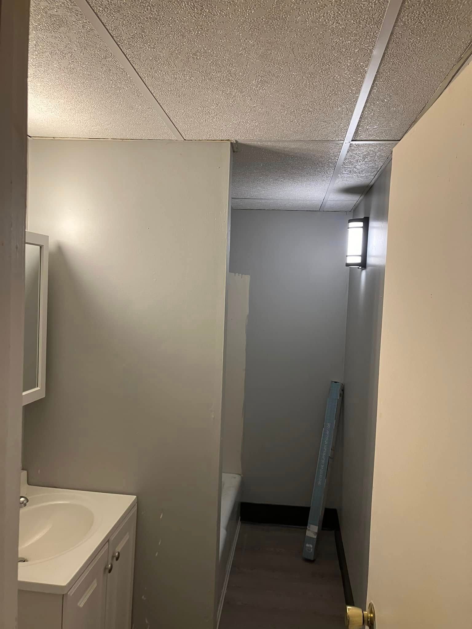 A bathroom with a sink , mirror and door.