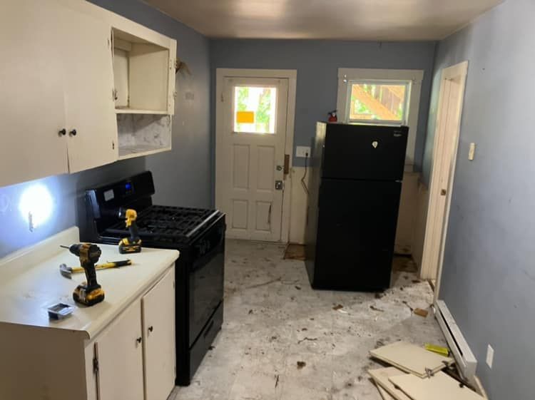 A kitchen with a black refrigerator and a stove