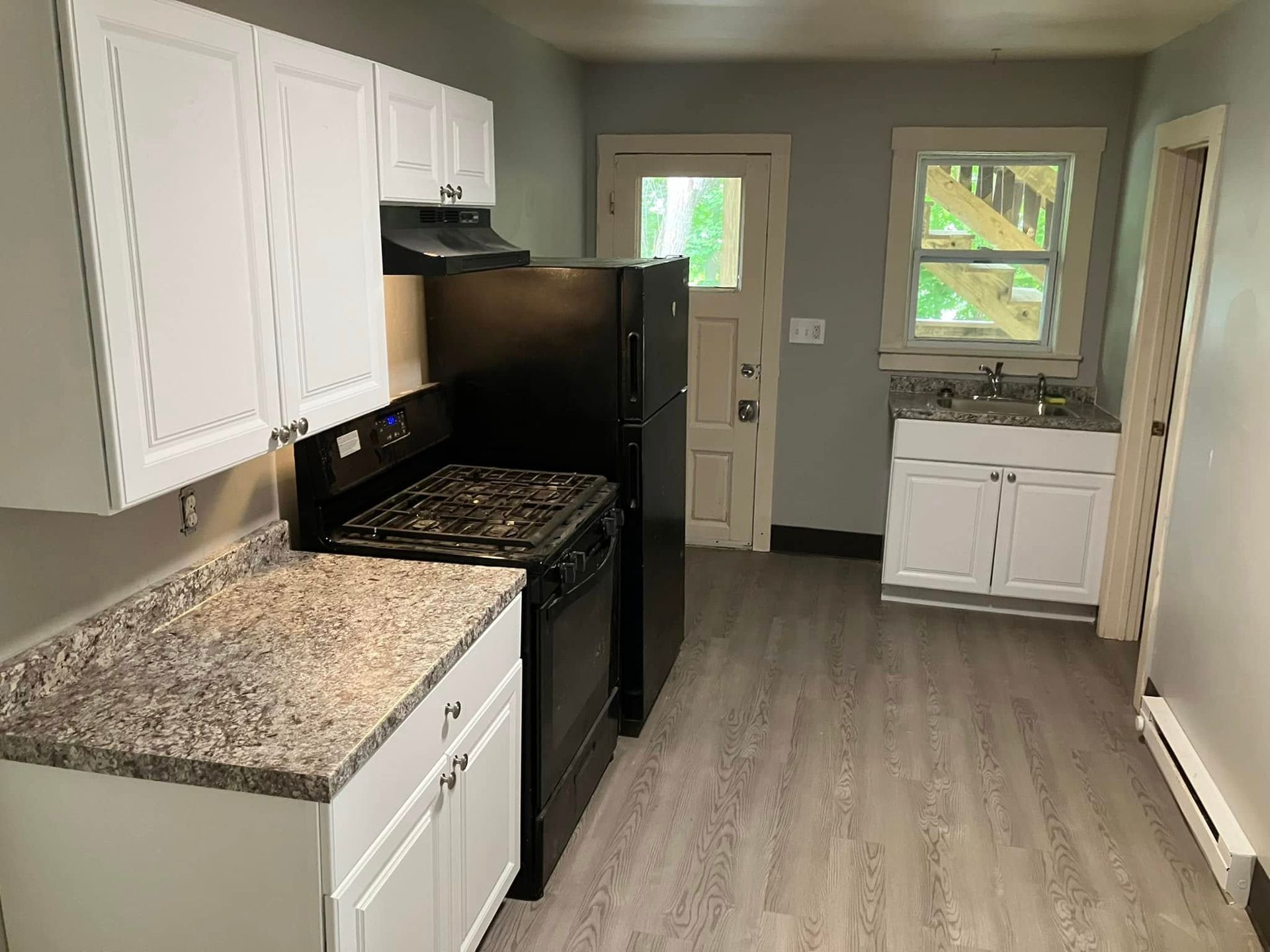 A kitchen with a stove , refrigerator , sink and cabinets.