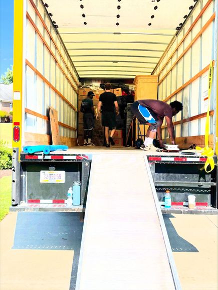 A moving truck filled with boxes and blue bags