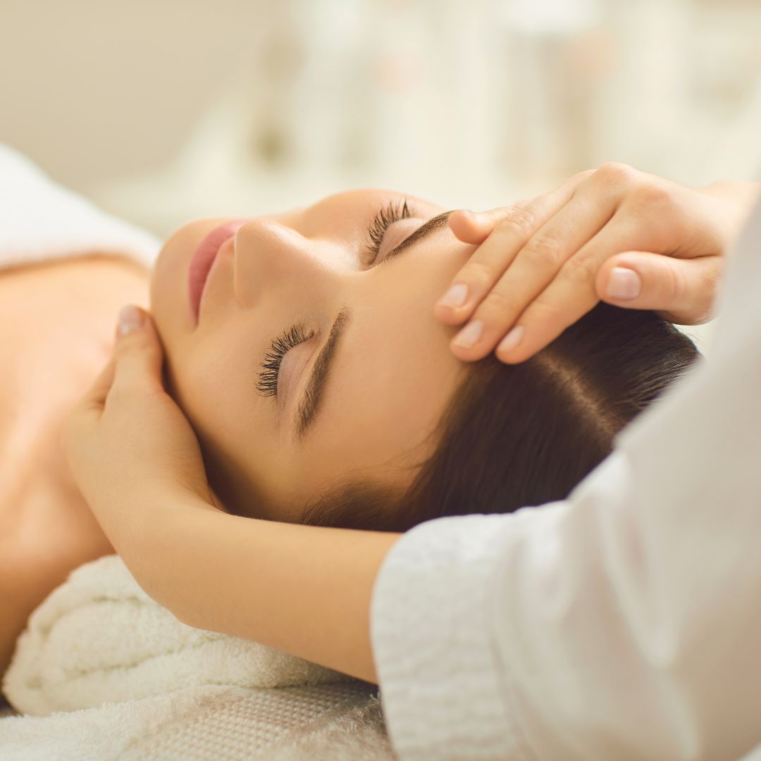 Eine Frau liegt auf einem Bett und bekommt eine Kopfmassage