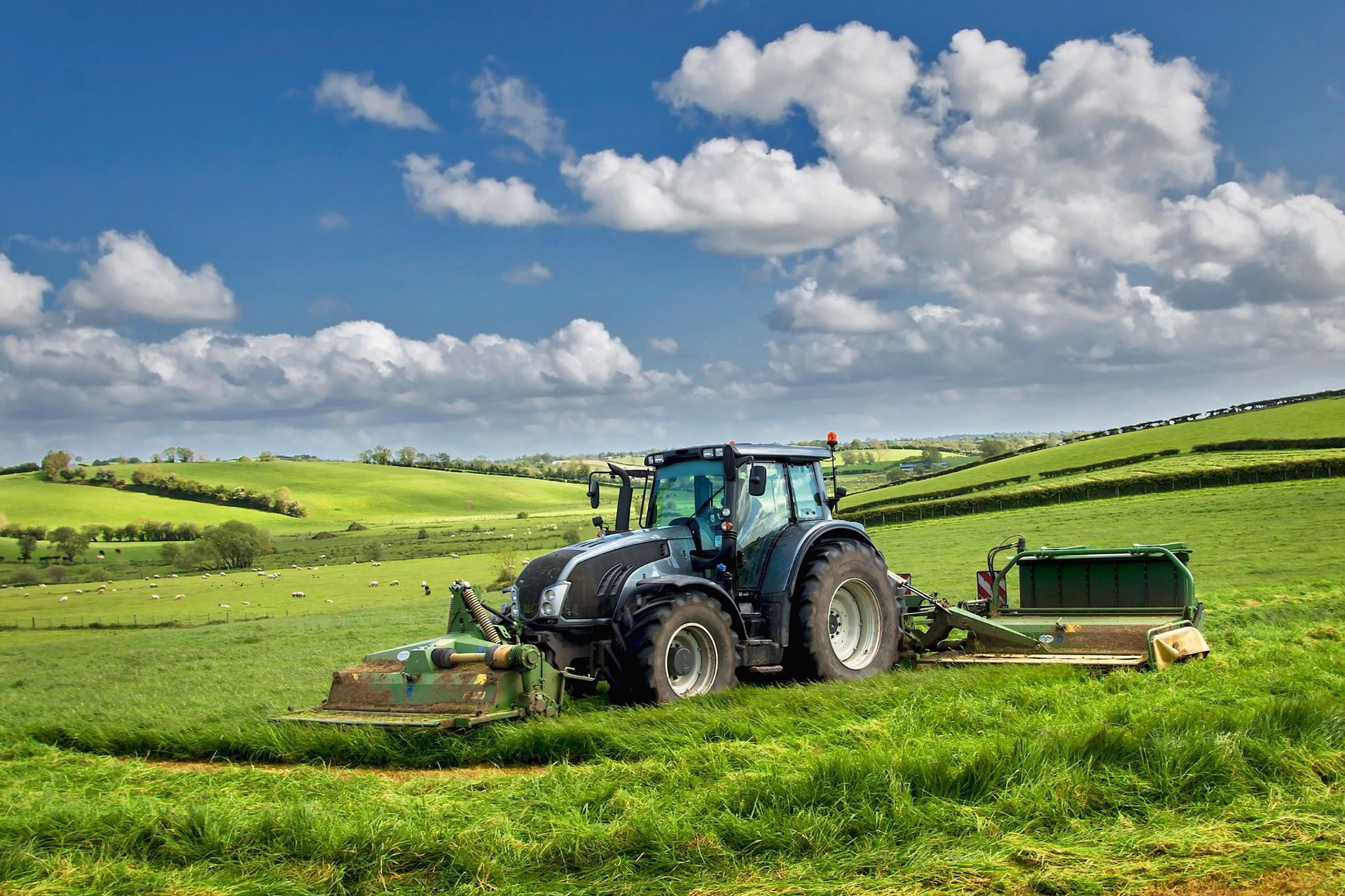 A tractor is cutting grass in a field on a sunny day.