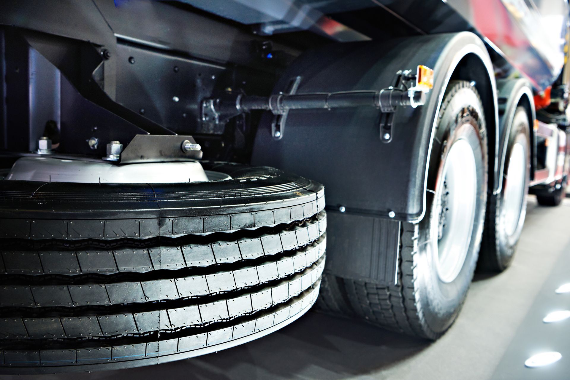 Close-up of a truck’s rear wheels and tires on a road, showing the undercarriage and wheel assembly.