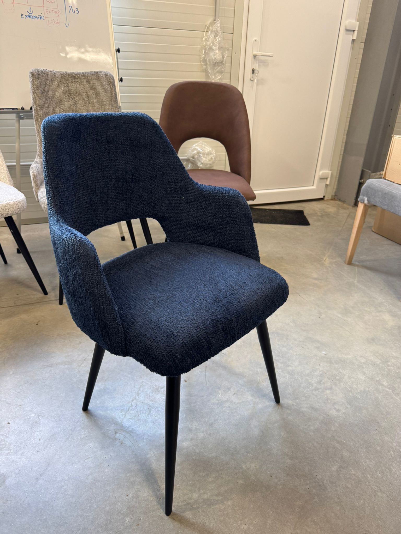 Una sedia blu è appoggiata sul pavimento di cemento in una stanza.