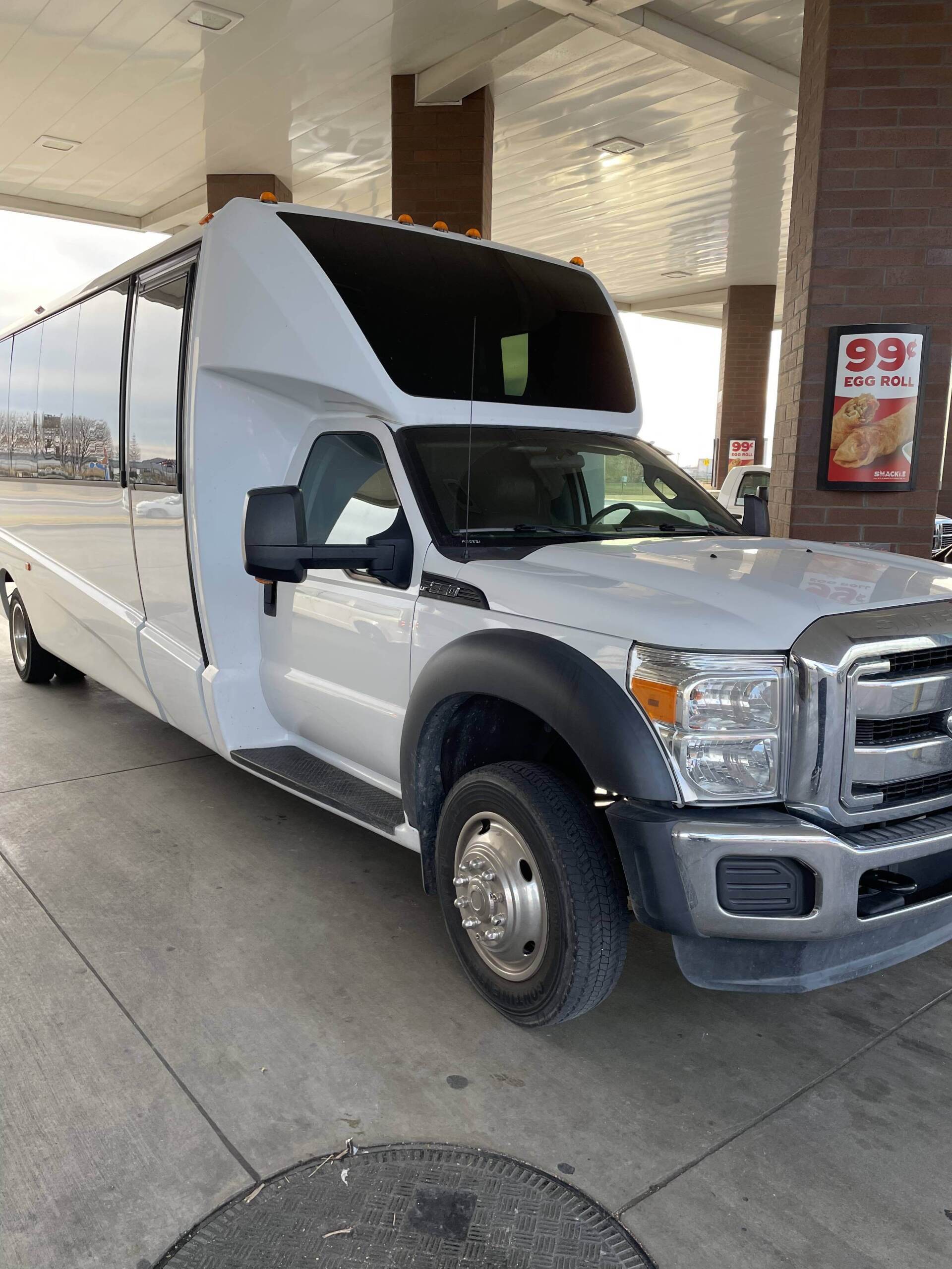 A white truck is parked in front of a gas station.