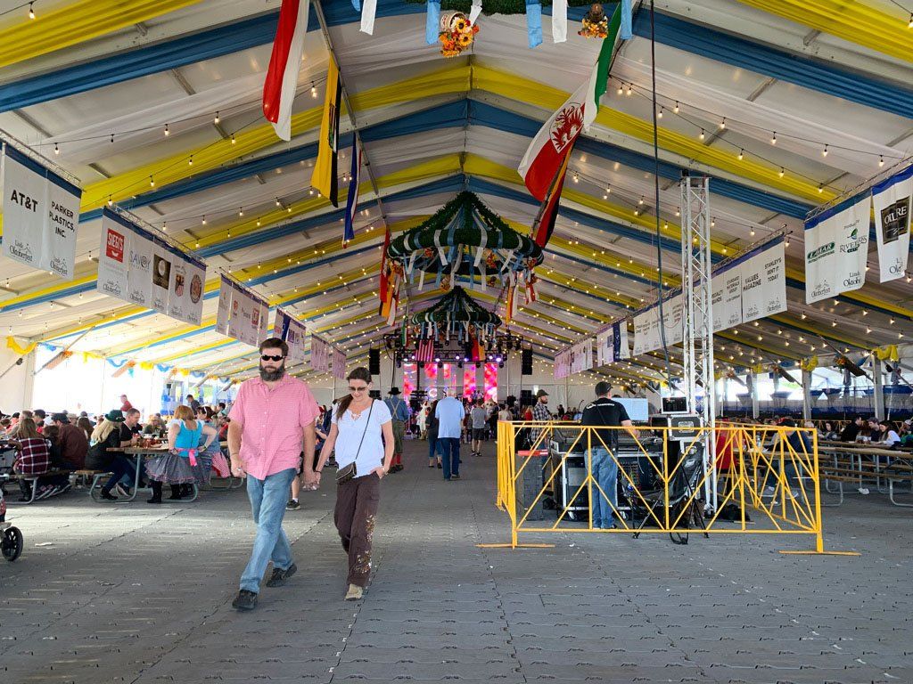 A group of people are walking through a large tent with flags hanging from the ceiling.